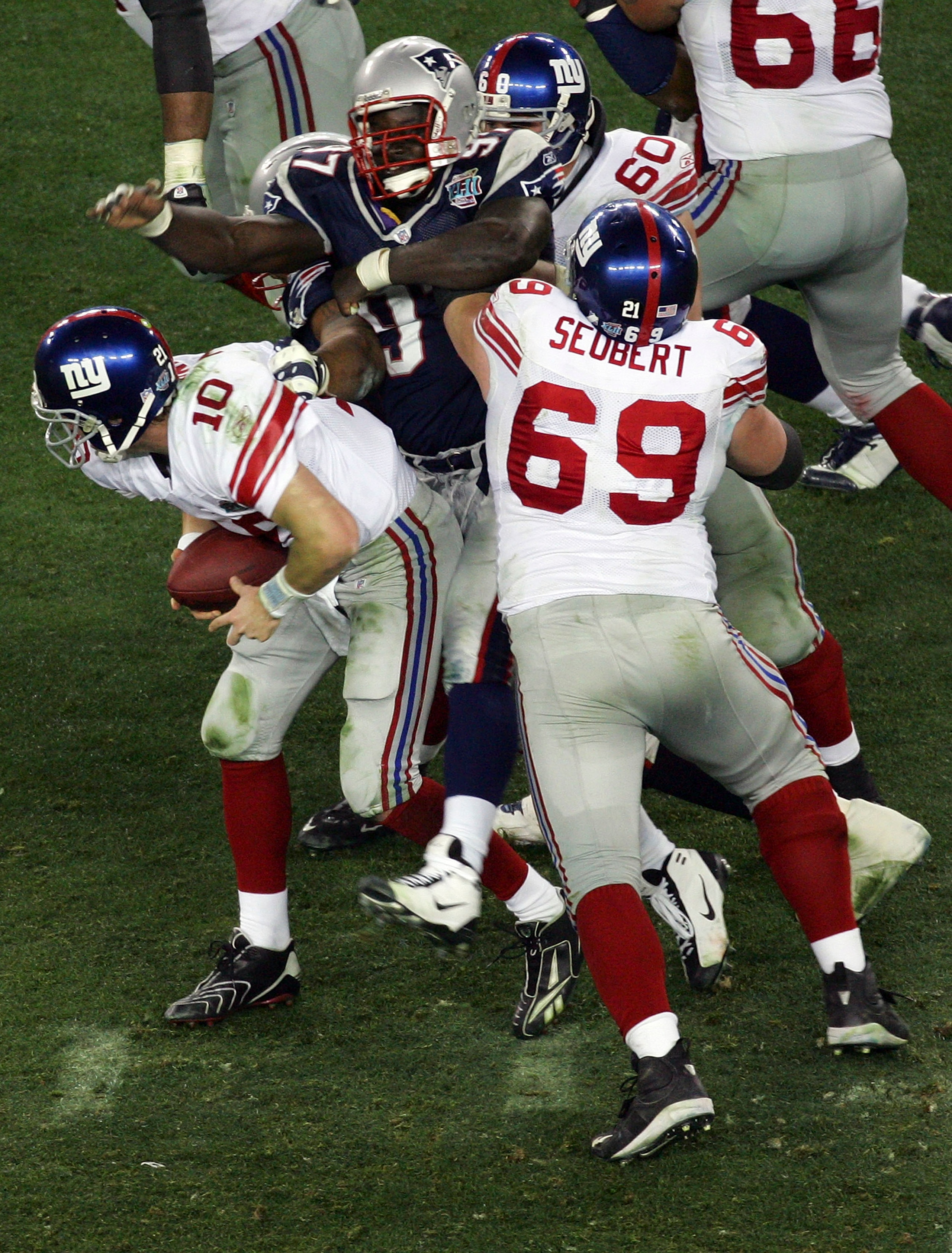 GLENDALE, AZ - FEBRUARY 03:  Eli Manning #10 of the New York Giants scrambles away from the New England Patriots defense to throw a 32-yard pass to David Tyree #85 of the Giants during the four quarter of Super Bowl XLII on February 3, 2008 at the Univers