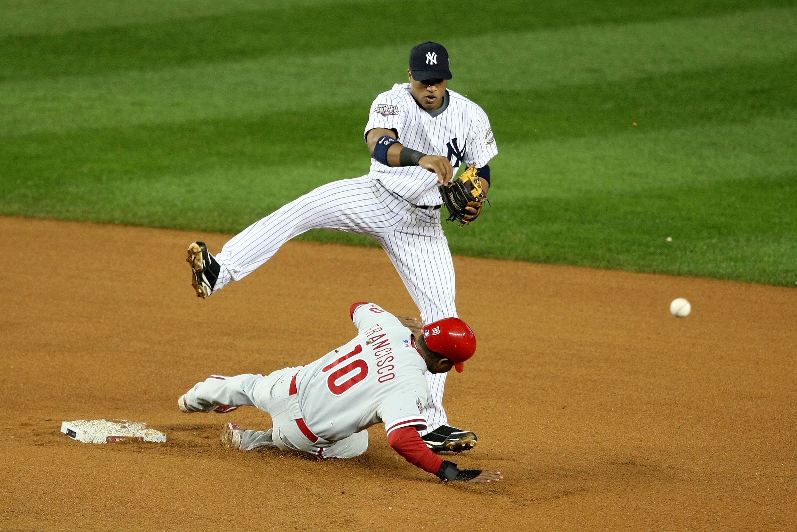 NEW YORK - OCTOBER 28:  Robinson Cano #24 of the New York Yankees turns a double play over a slifind Ben Francisco #10 of the Philadelphia Phillies on a ball hit by Pedro Feliz #7 in the top of the seventh inning of Game One of the 2009 MLB World Series a