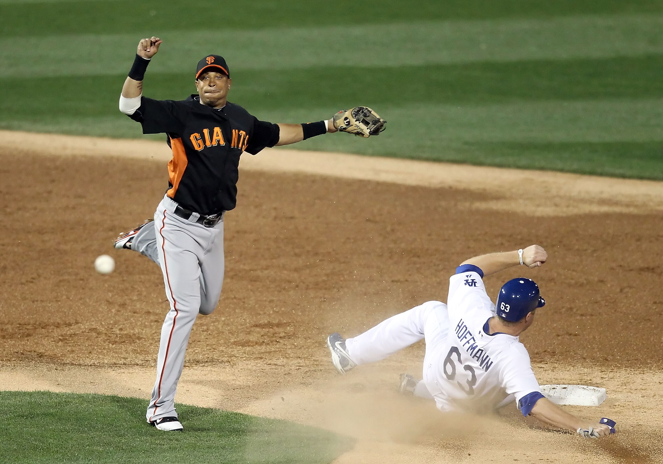 GLENDALE, AZ - MARCH 04:  Infielder Emmanuel Burriss #2 of the San Francisco Giants throws over the sliding Jamie Hoffmann #63 of the Los Angeles Dodgers to complete a double play during the second inning of the spring training game at Camelback Ranch on
