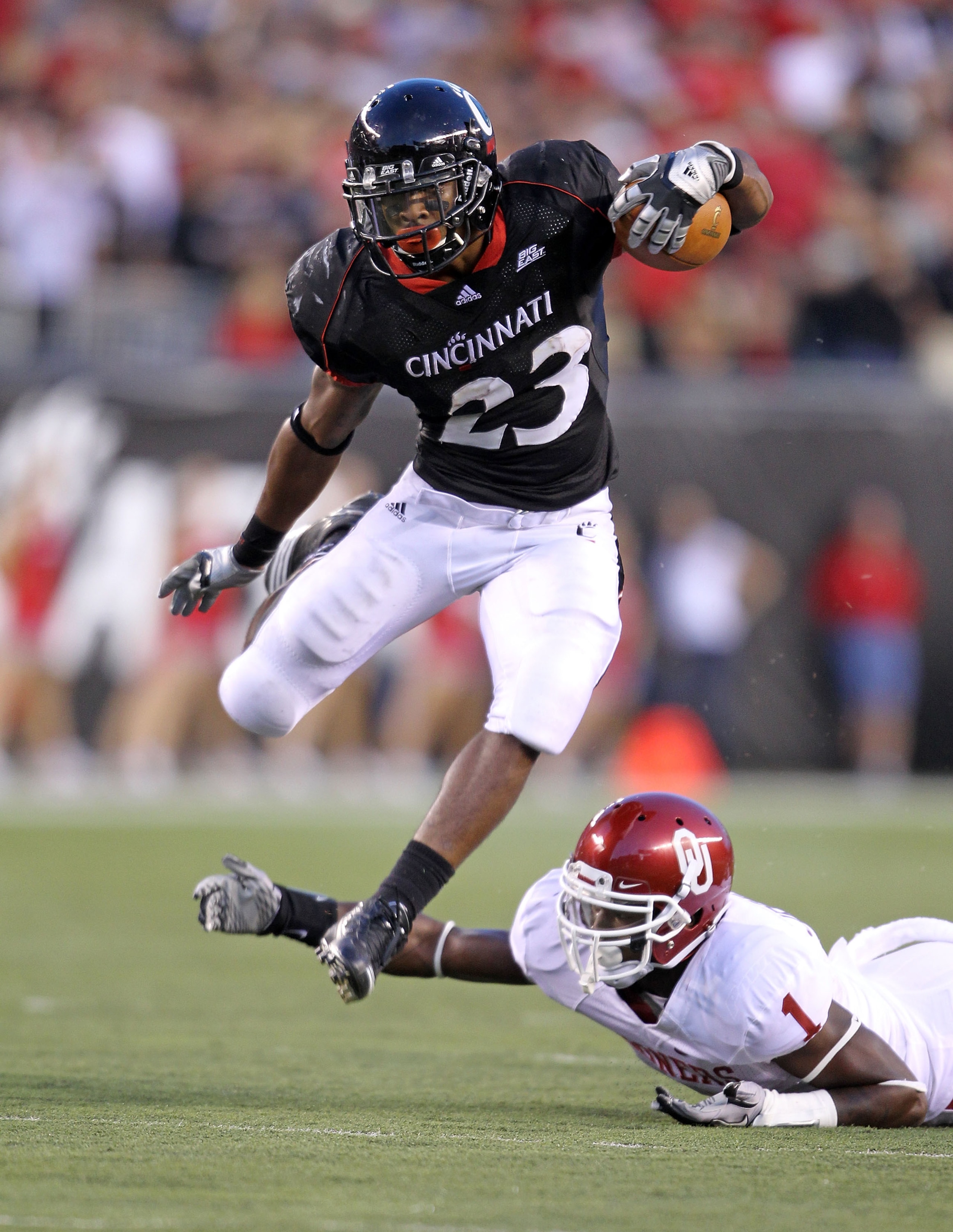 CINCINNATI - SEPTEMBER 25: Isaiah Pead #23 of the Cincinnati Bearcats runs with the ball while defended by Tony Jefferson #1 of the Oklahoma Sooners at Paul Brown Stadium on September 25, 2010 in Cincinnati, Ohio.  (Photo by Andy Lyons/Getty Images)