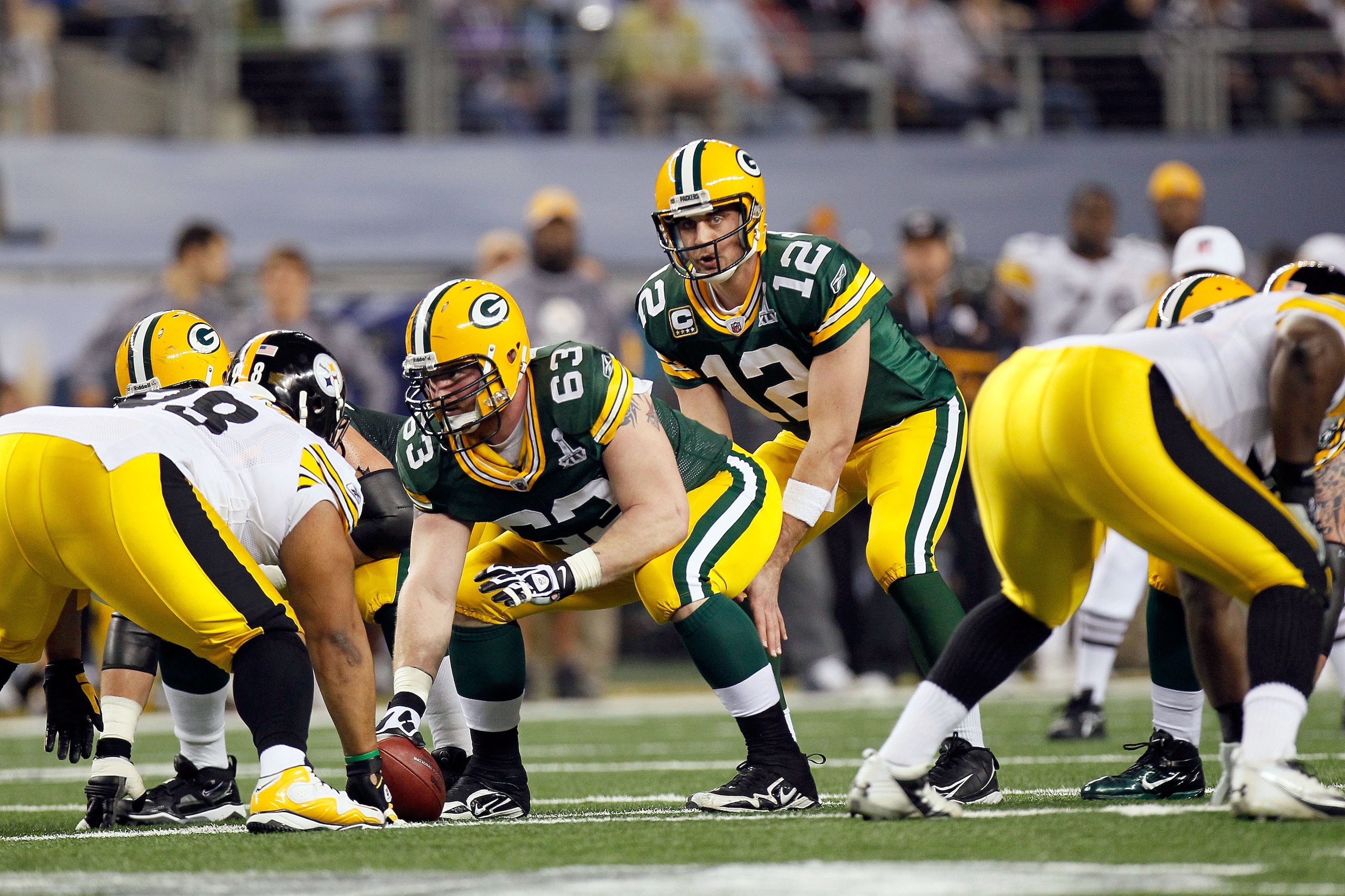 ARLINGTON, TX - FEBRUARY 06:  Aaron Rodgers #12 of the Green Bay Packers calls signals at the line of scrimmage under center Scott Wells #63 against the Pittsburgh Steelers during Super Bowl XLV at Cowboys Stadium on February 6, 2011 in Arlington, Texas.