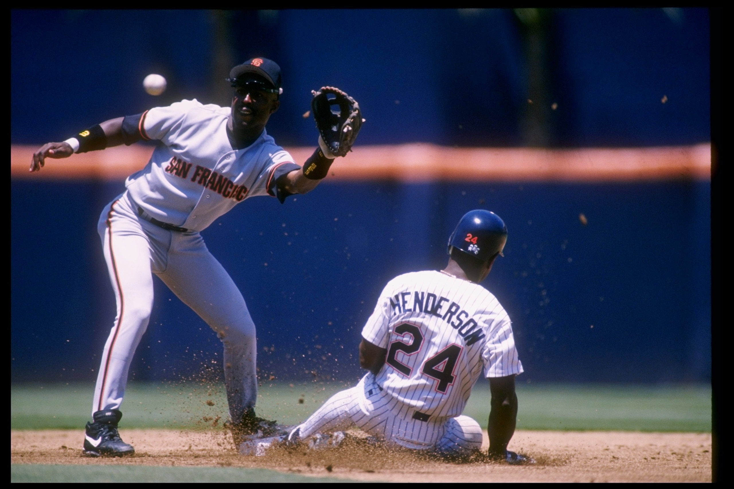 4 Jul 1996:  Shortstop Shawon Dunston of the San Francisco Giants (left) reaches out to catch the ball as outfielder Rickey Henderson of the San Diego Padres slides toward base during a game at Jack Murphy Stadium in San Diego, California.  The Padres won