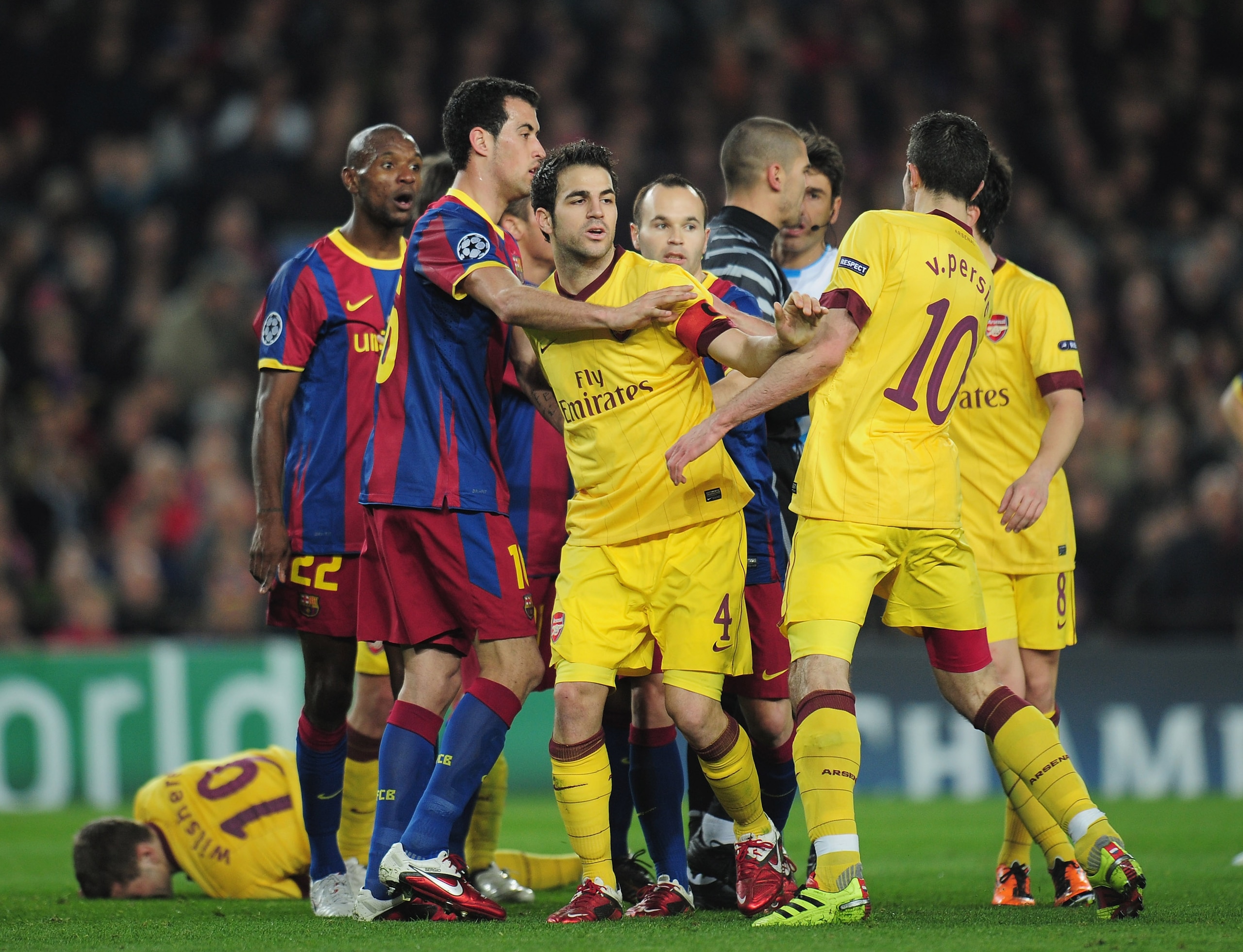 BARCELONA, SPAIN - MARCH 08:  Arsenal captain Cesc Fabregas steps in between Sergio Busquets of Barcelona and team-mate Robin van Persie during the UEFA Champions League round of 16 second leg match between Barcelona and Arsenal at the Nou Camp Stadium on