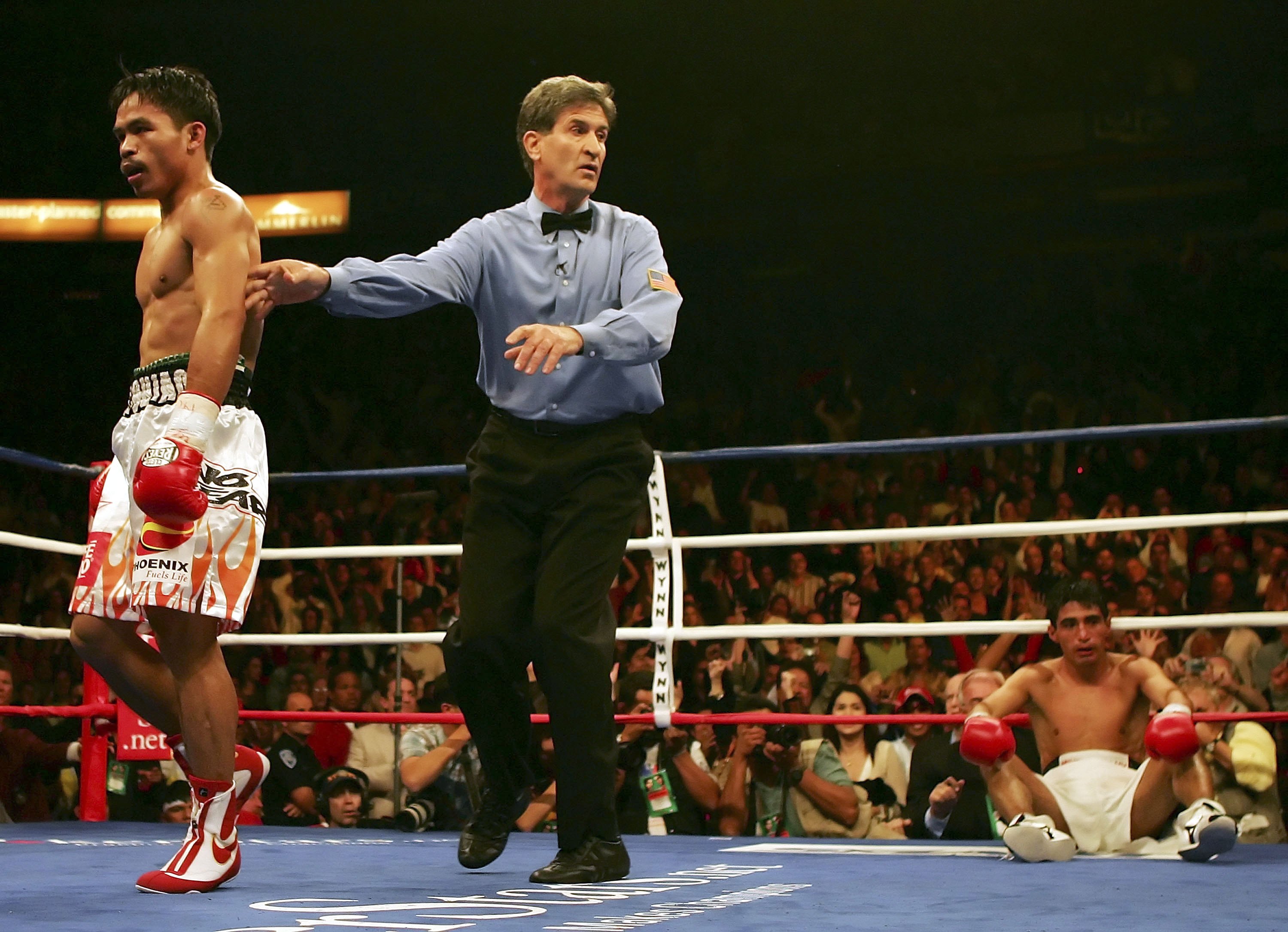 LAS VEGAS - NOVEMBER 18: (L-R) Manny Pacquiao of the Philippines is directed to his corner by referee Vic Drakulich as Erik Morales of Mexico is knocked down for the second time in round three during their super featherweight bout at the Thomas & Mack Ce