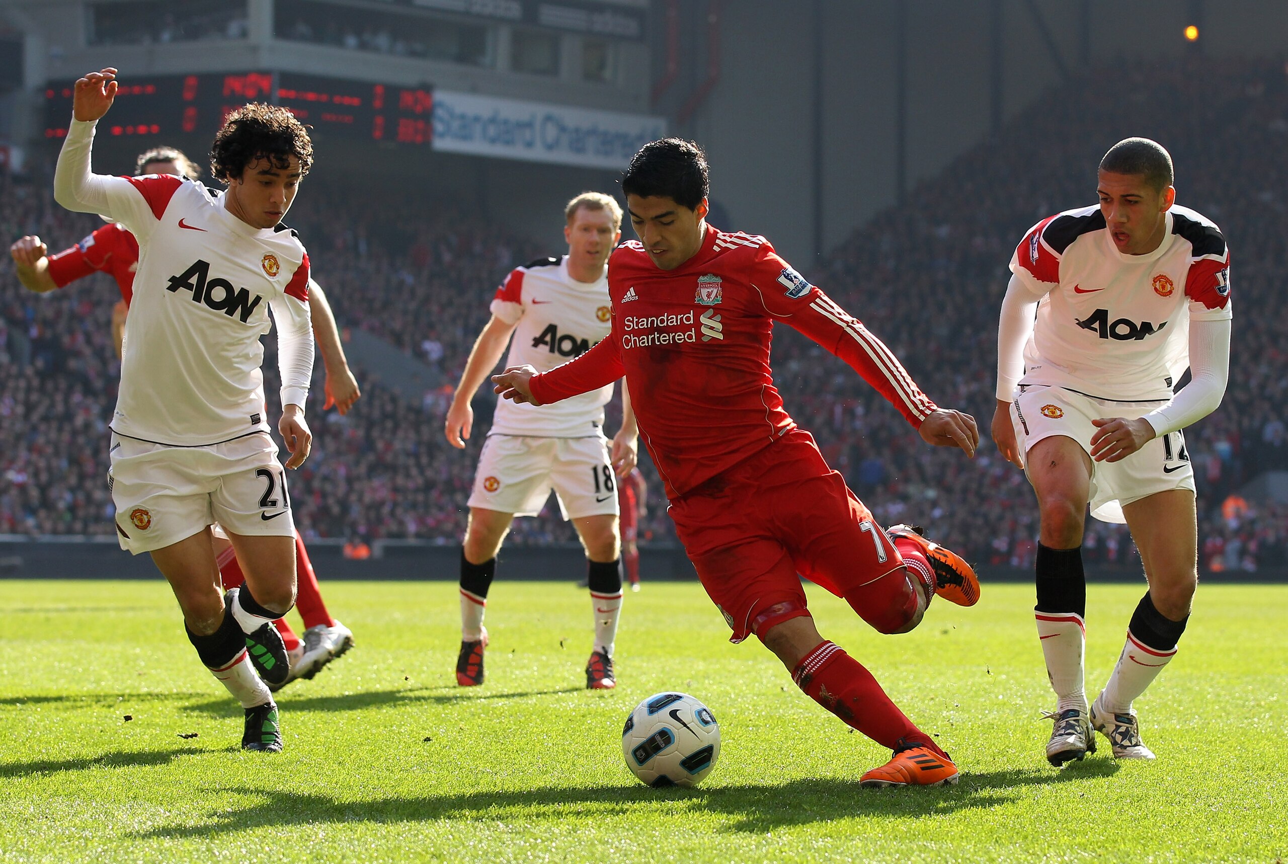 LIVERPOOL, ENGLAND - MARCH 06:  Luis Suarez of Liverpool goes clear of Chris Smalling and Rafael (L) of Manchester United to set up the first goal during the Barclays Premier League match between Liverpool and Manchester United at Anfield on March 6, 2011