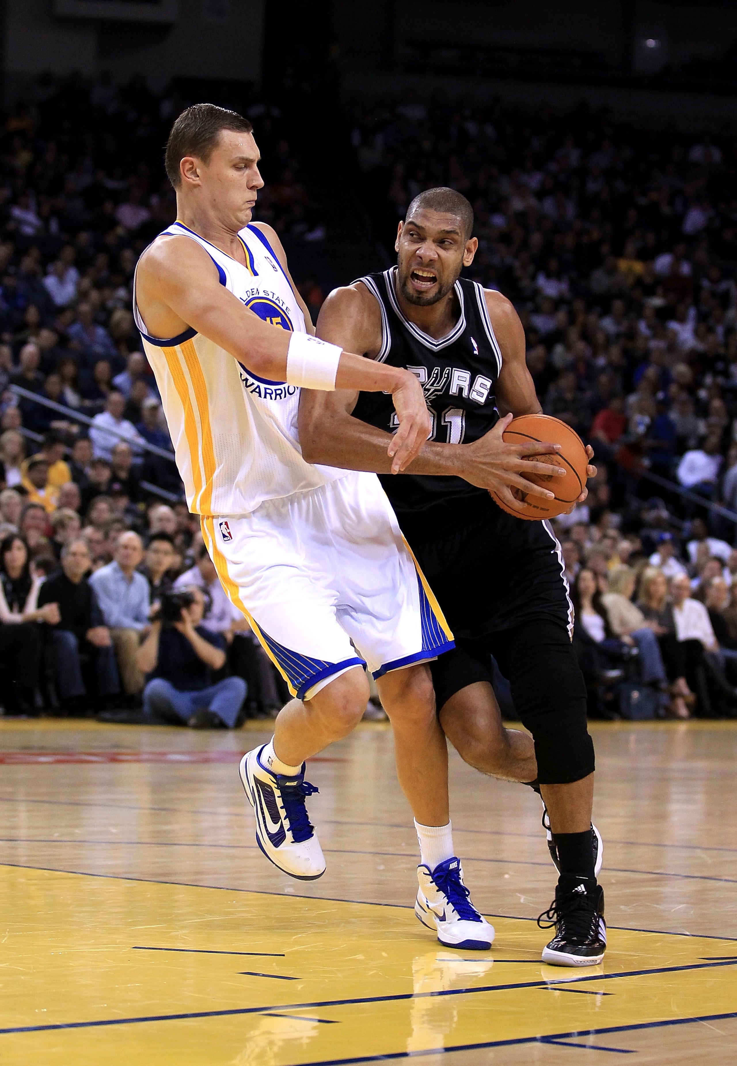 OAKLAND, CA - JANUARY 24:  Tim Duncan #21 of the San Antonio Spurs is fouled by Andris Biedrins #15 of the Golden State Warriors at Oracle Arena on January 24, 2011 in Oakland, California.  NOTE TO USER: User expressly acknowledges and agrees that, by dow