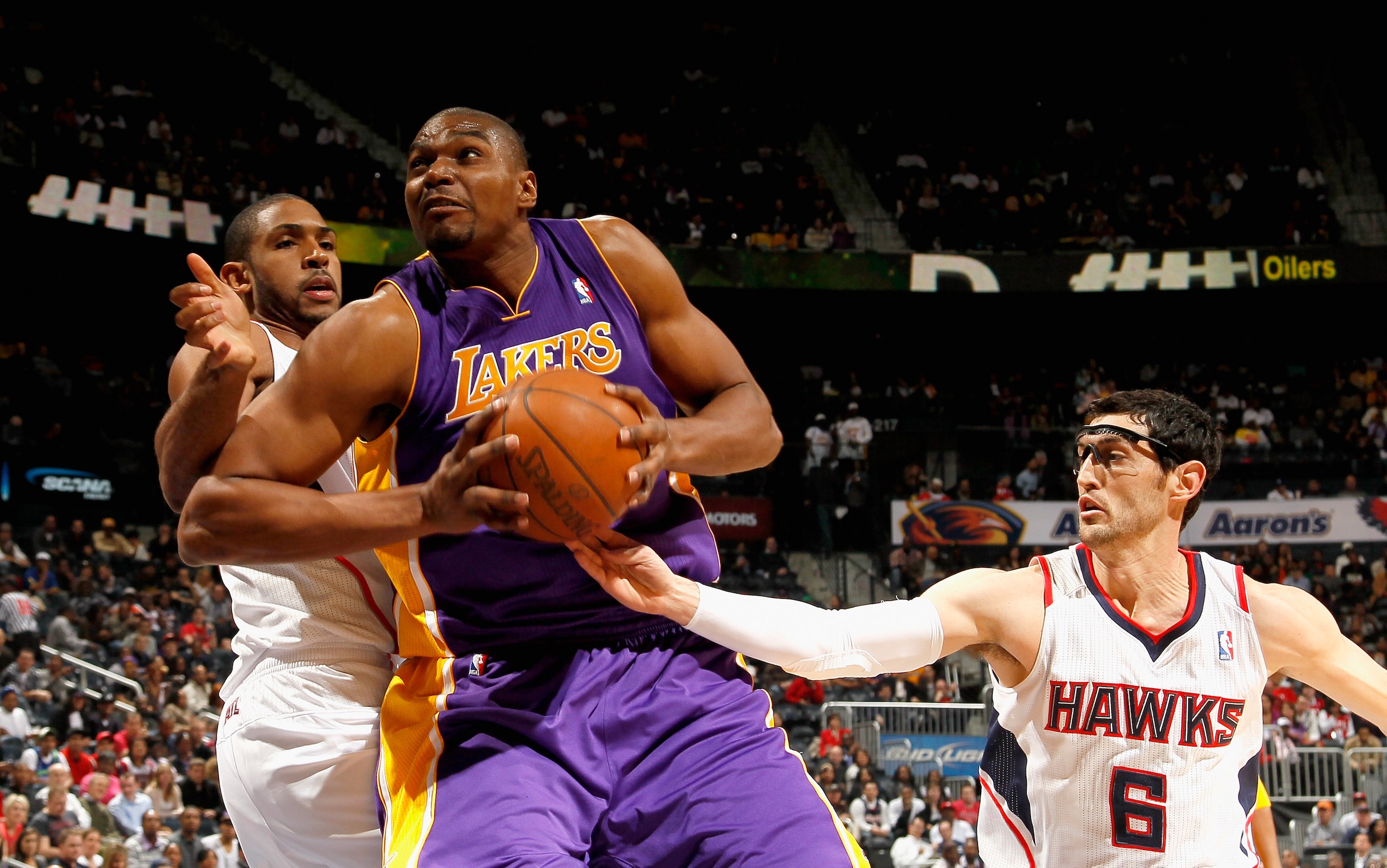 ATLANTA, GA - MARCH 08:  Andrew Bynum #17 of the Los Angeles Lakers drives between Al Horford #15 and Kirk Hinrich #6 of the Atlanta Hawks at Philips Arena on March 8, 2011 in Atlanta, Georgia.  NOTE TO USER: User expressly acknowledges and agrees that, b