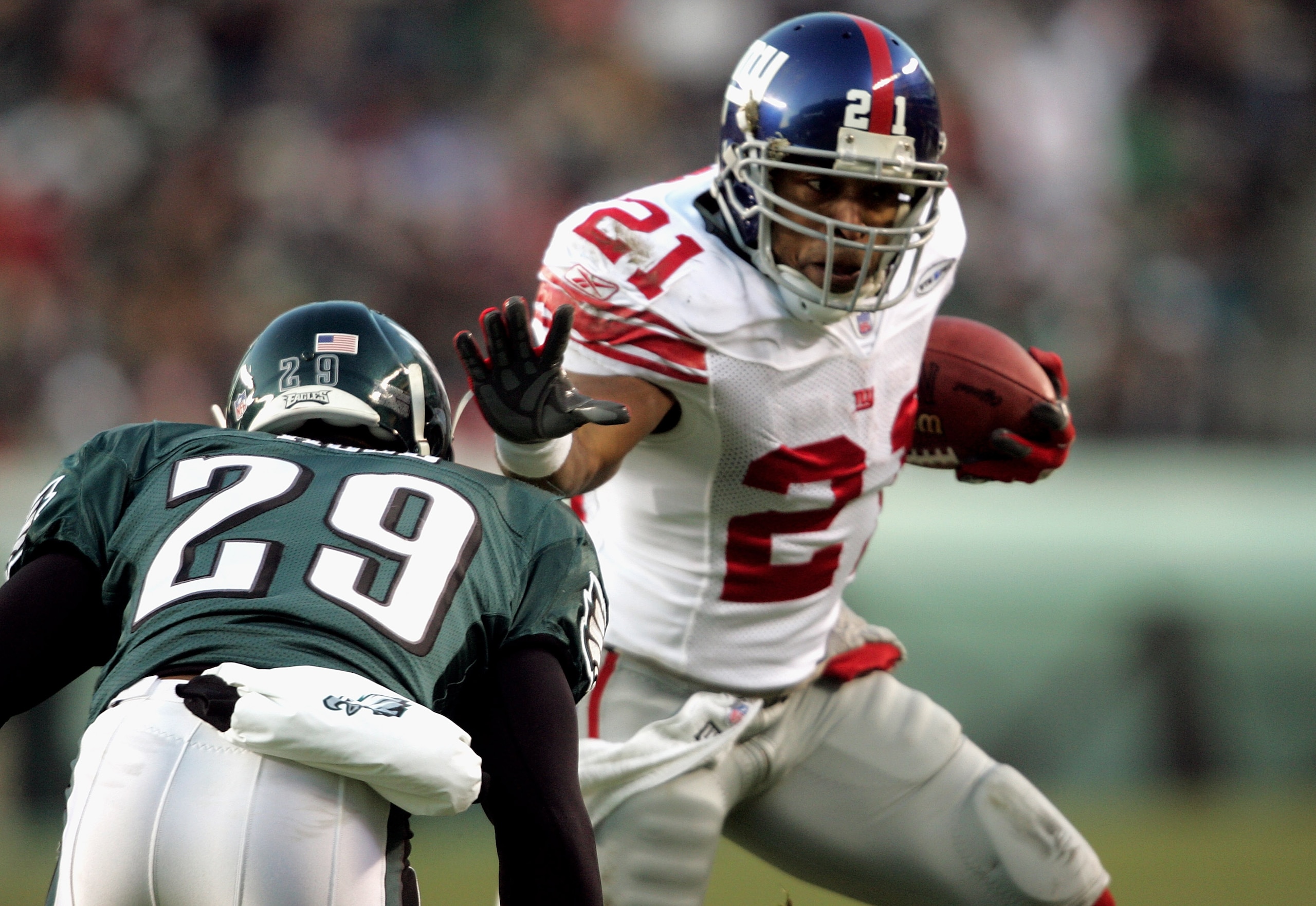 PHILADELPHIA - DECEMBER 11:  Running back Tiki Barber #21 of the New York Giants carries the ball past  Roderick Hood #29 of the Philadelphia Eagles during the first quarter of the game on December 11, 2005 at Lincoln Financial Field in Philadelphia, Penn