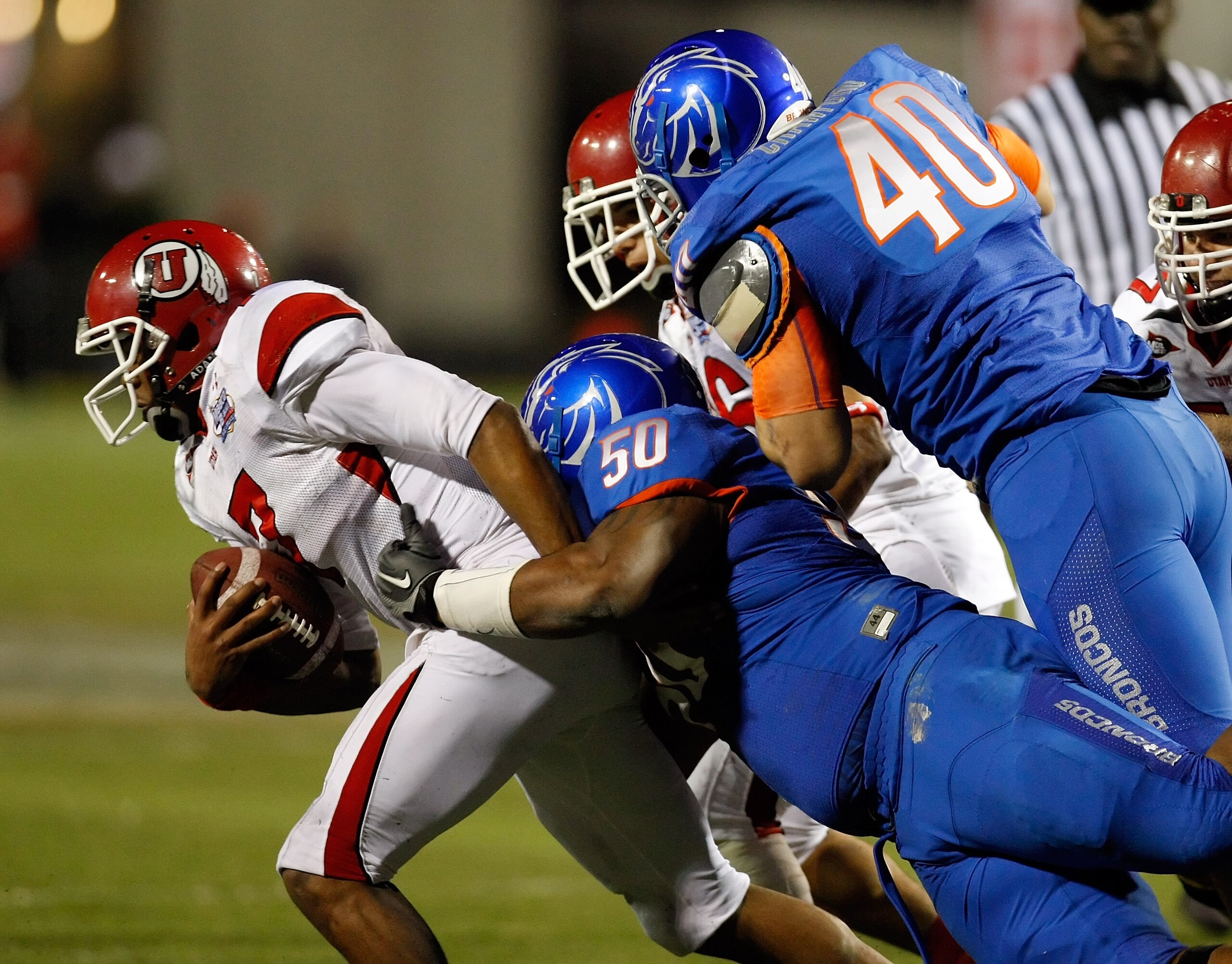 LAS VEGAS, NV - DECEMBER 22:  Quarterback Terrance Cain #7 of the Utah Utes is sacked by J.P. Nisby #50 of the Boise State Broncos as Boise State's Tyrone Crawford #40 defends during the MAACO Bowl Las Vegas at Sam Boyd Stadium December 22, 2010 in Las Ve