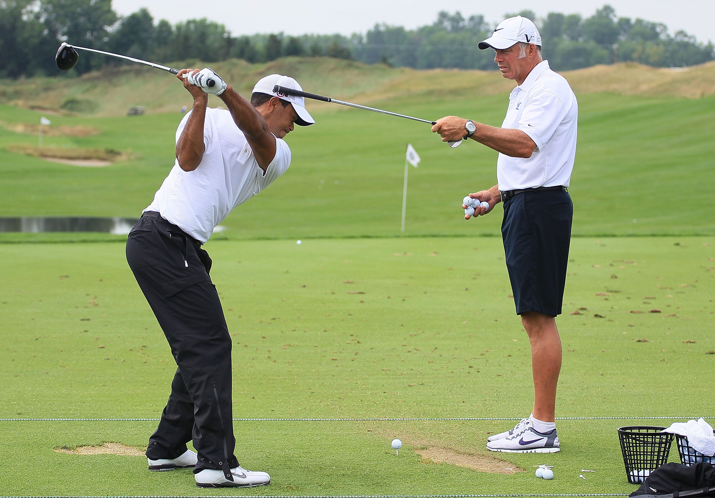 KOHLER, WI - AUGUST 11:  Tiger Woods works on his swing with his caddie Steve Williams (R) on the practice ground during a practice round prior to the start of the 92nd PGA Championship on the Straits Course at Whistling Straits on August 11, 2010 in Kohl