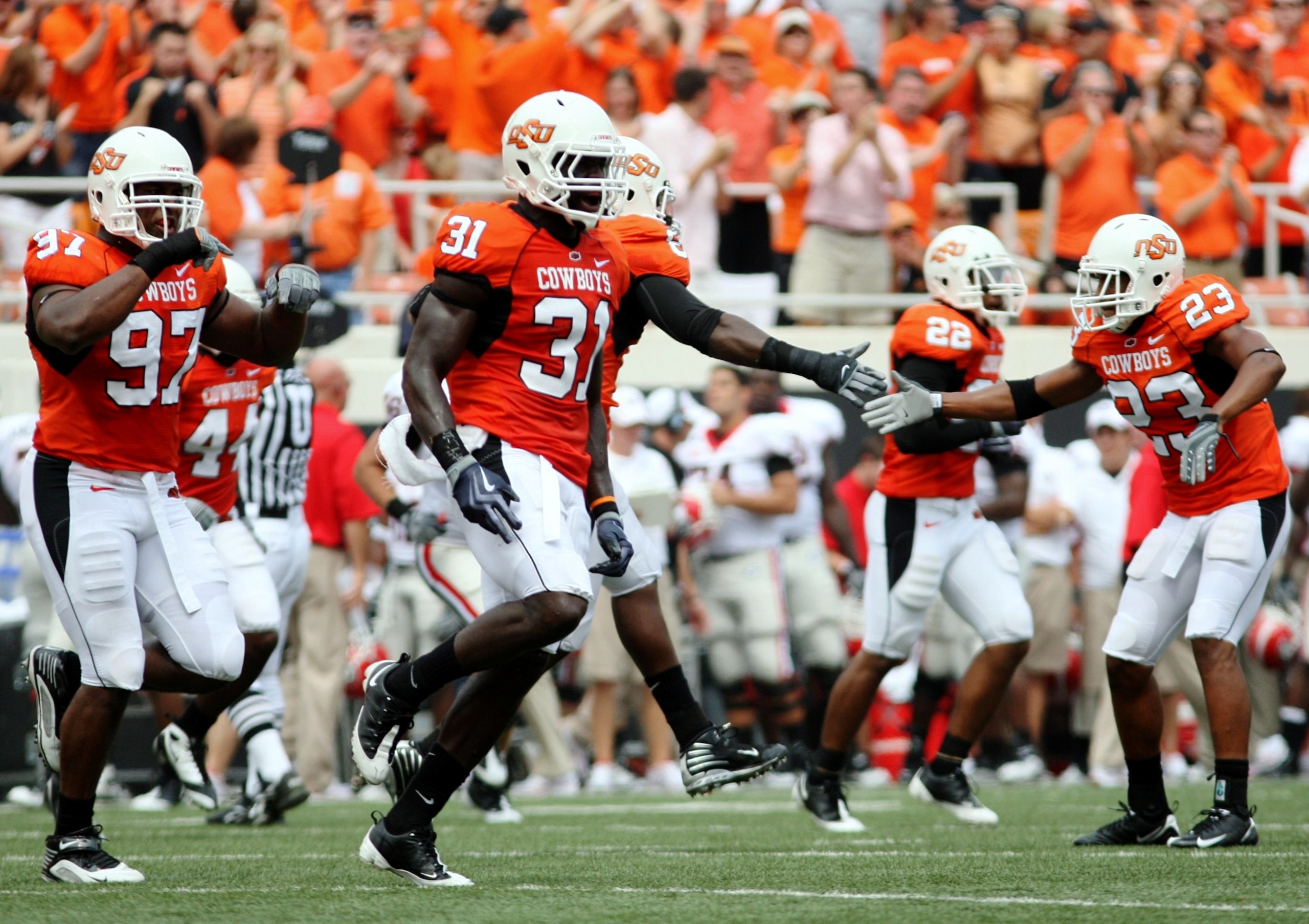 STILLWATER, OK - SEPTEMBER 5:  Lucien Antoine #31, Jeremiah Price #97 and Terrance Anderson #23 of the  Oklahoma State Cowboys defense celebrate a third down stop to force a fourth down in the first quarter of the game against the Georgia Bulldogs at Boon