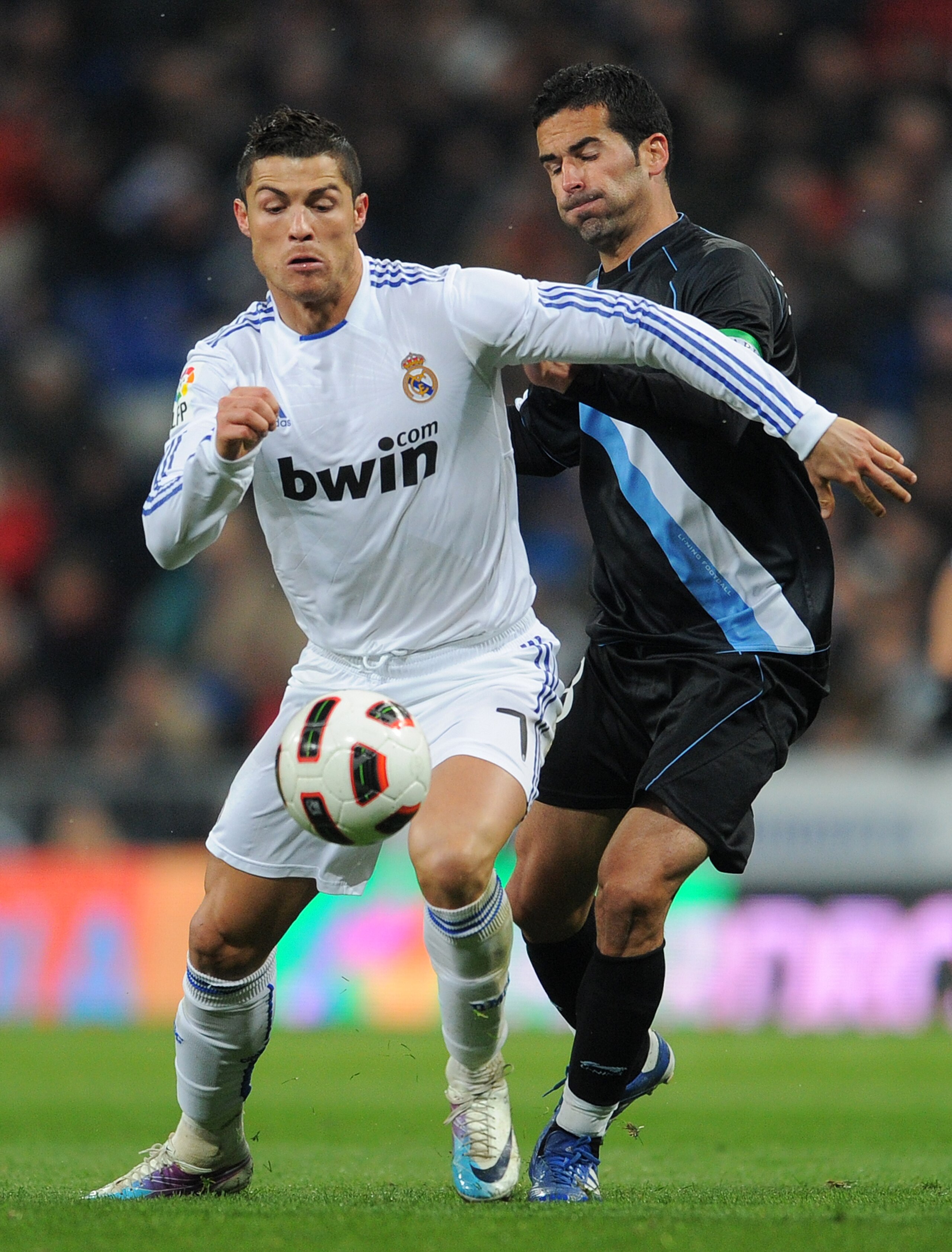 MADRID, SPAIN - MARCH 03:  Cristiano Ronaldo (L) of Real Madrid fights for the ball with Fernando Escribano of Malaga during the la Liga match between Real Madrid and Malaga at Estadio Santiago Bernabeu on March 3, 2011 in Madrid, Spain.  (Photo by Jasper