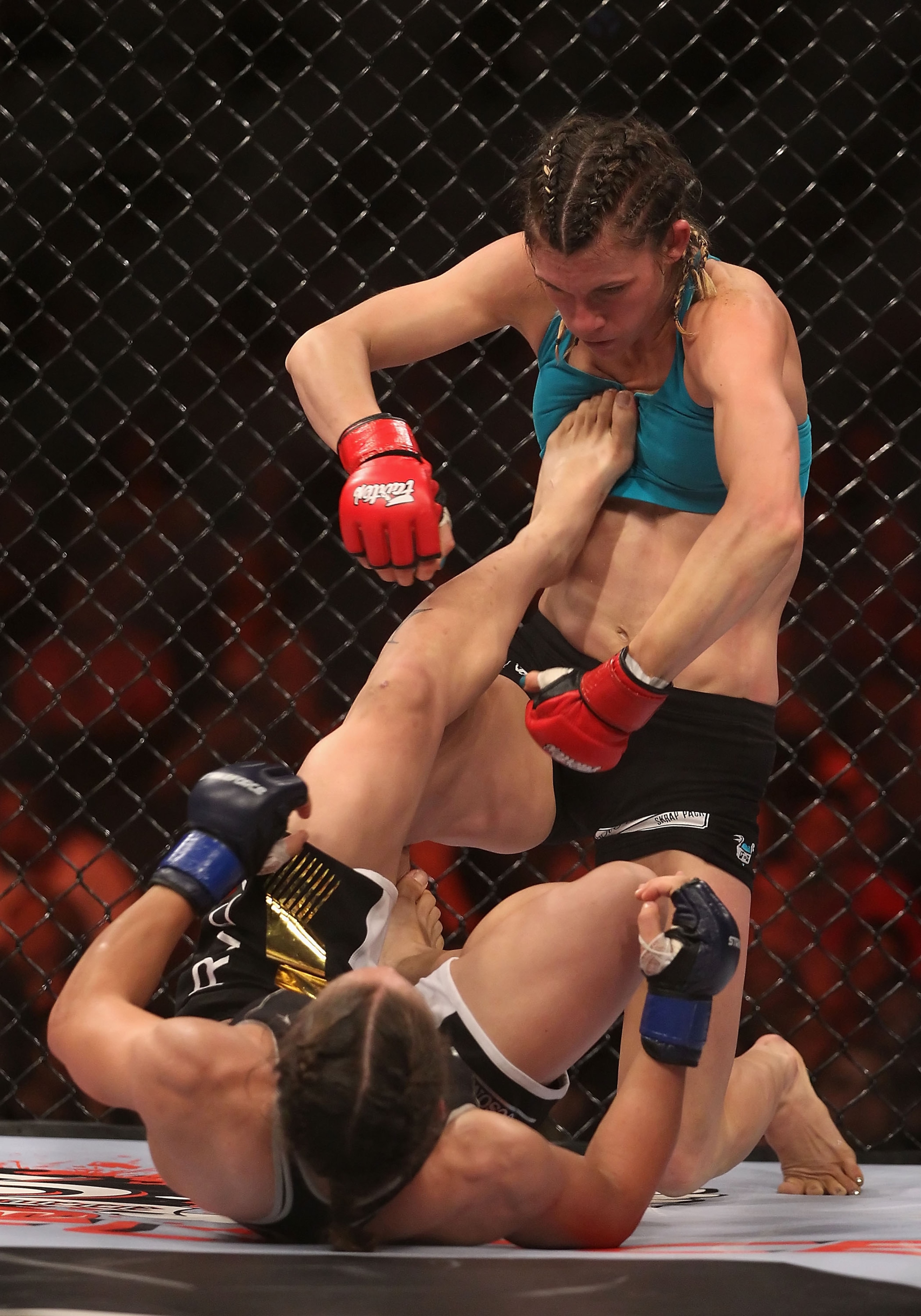 PHOENIX - AUGUST 13:  Colleen Schnieder is kicked by Liz Carmouche during the Strikeforce Challengers Undercard bout at Dodge Theater on August 13, 2010 in Phoenix, Arizona.  (Photo by Christian Petersen/Getty Images)