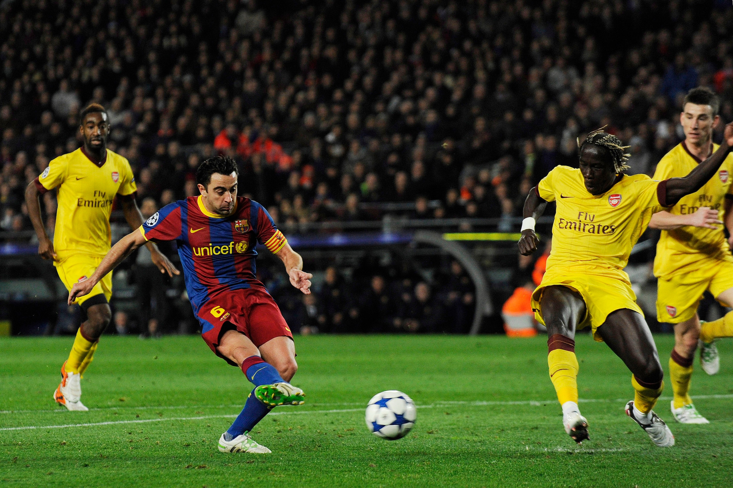 BARCELONA, SPAIN - MARCH 08: Xavi Hernandez of FC Barcelona (2ndL) scores his team's second goal under a challenge by Bacary Sagna of Arsenal during the UEFA Champions League round of 16 second leg match between Barcelona and Arsenal at the Camp Nou stadi