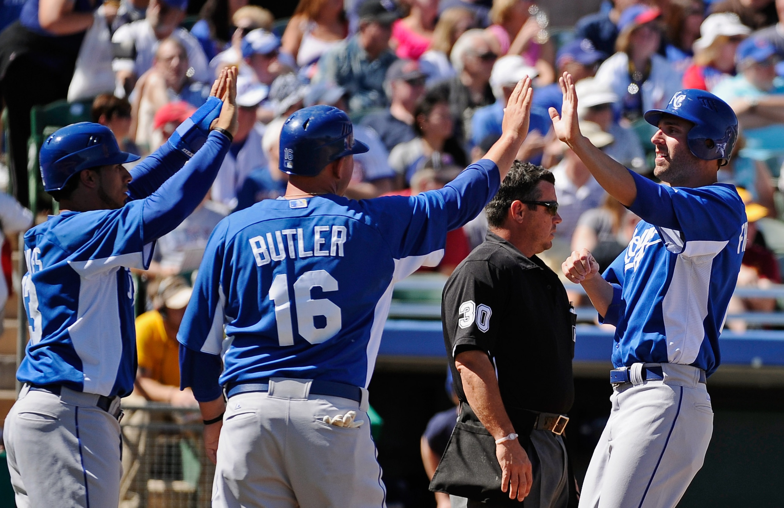 MESA, AZ - MARCH 09:  Mike Aviles #13, Billy Butler #16 and Jeff Francoeur #21 of the Kansas City Royals celebrate after they all scored on a triple by teammate Melky Cabrera #53 in the first inning against pitcher Matt Garza #17 of the Chicago Cubs durin