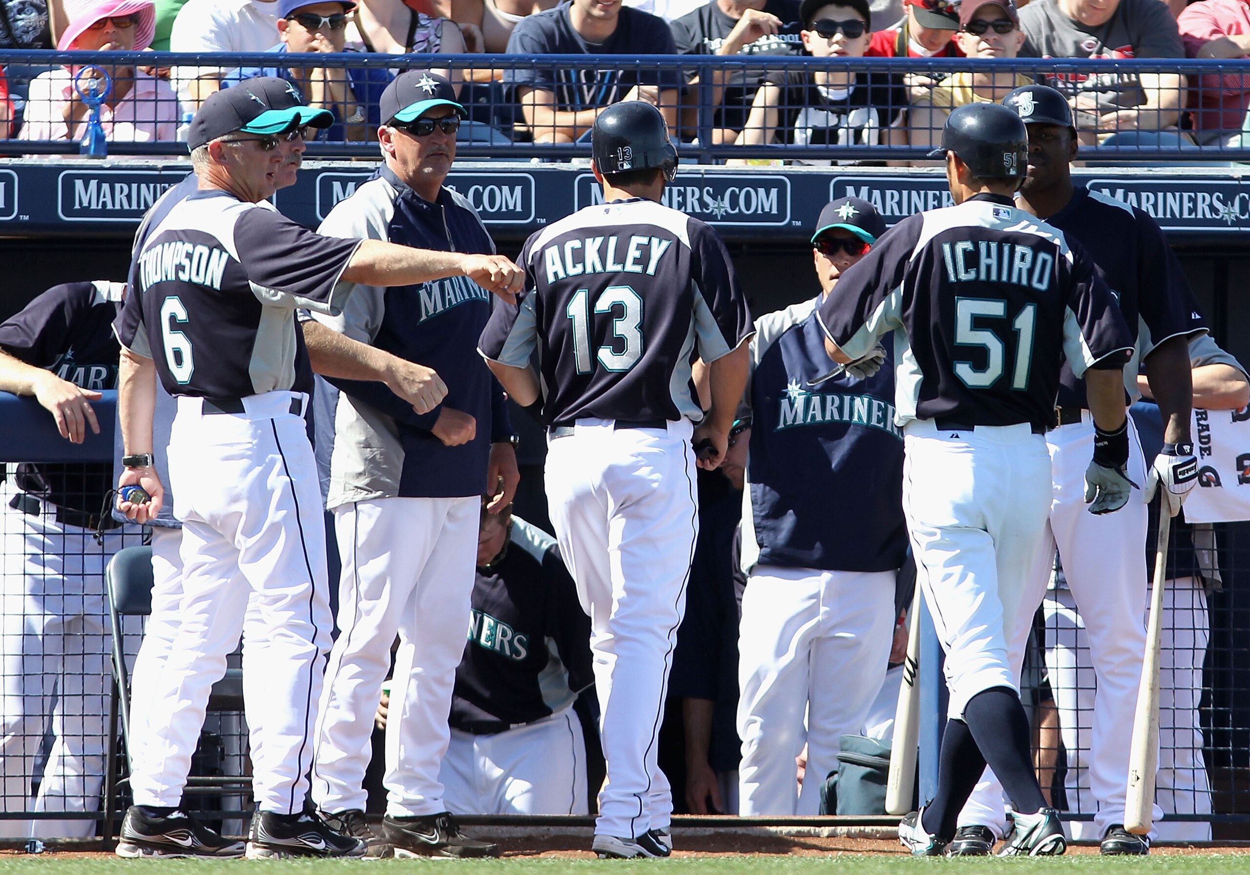 PEORIA, AZ - MARCH 04:  Dustin Ackley #13 of the Seattle Mariners is congratulated by teammates after scoring a run on a sacrifice fly hit by Ichiro Suzuki #51 during the third inning of the spring training game against the Cincinnati Reds at Peoria Stadi
