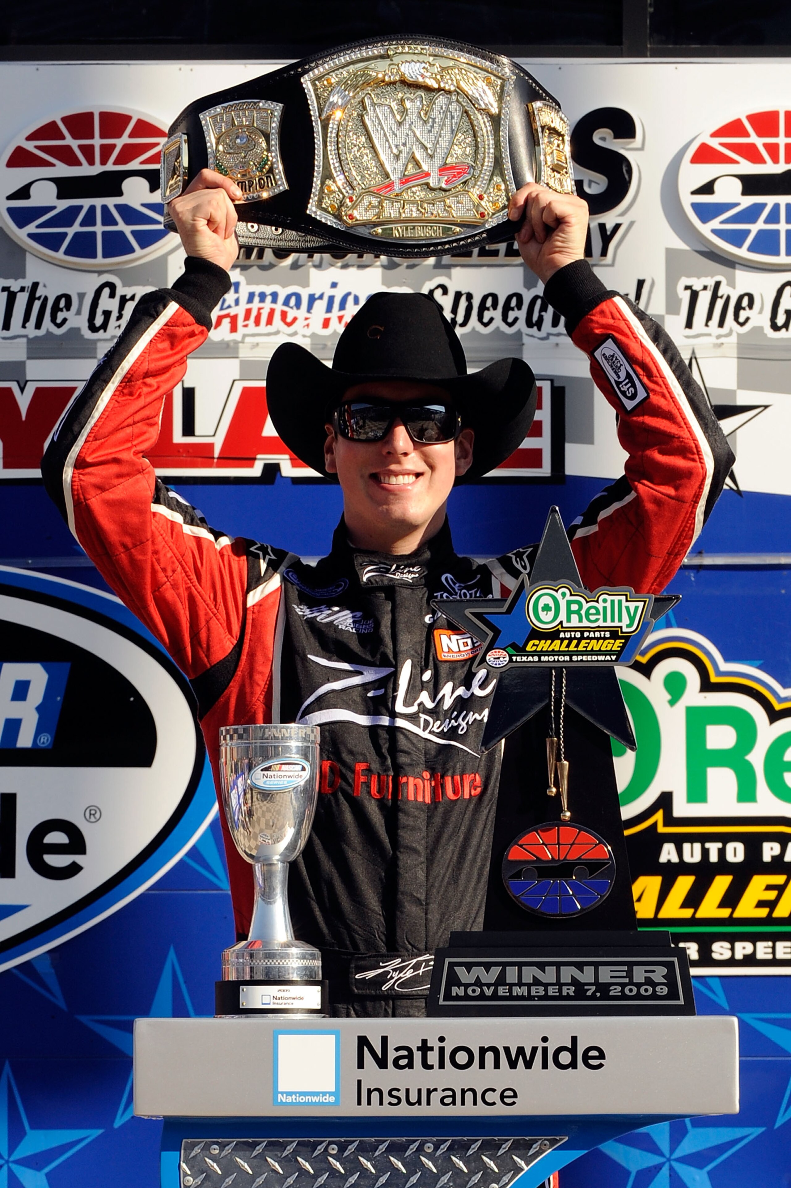 FORT WORTH, TX - NOVEMBER 07:  Kyle Busch, driver of the #18 Z-Line Designs/WWE Smackdown Toyota,  hoist a replica of the WWE world championship belt on victory lane after winning the NASCAR Nationwide Series O'Reilly Challenge at Texas Motor Speedway on 