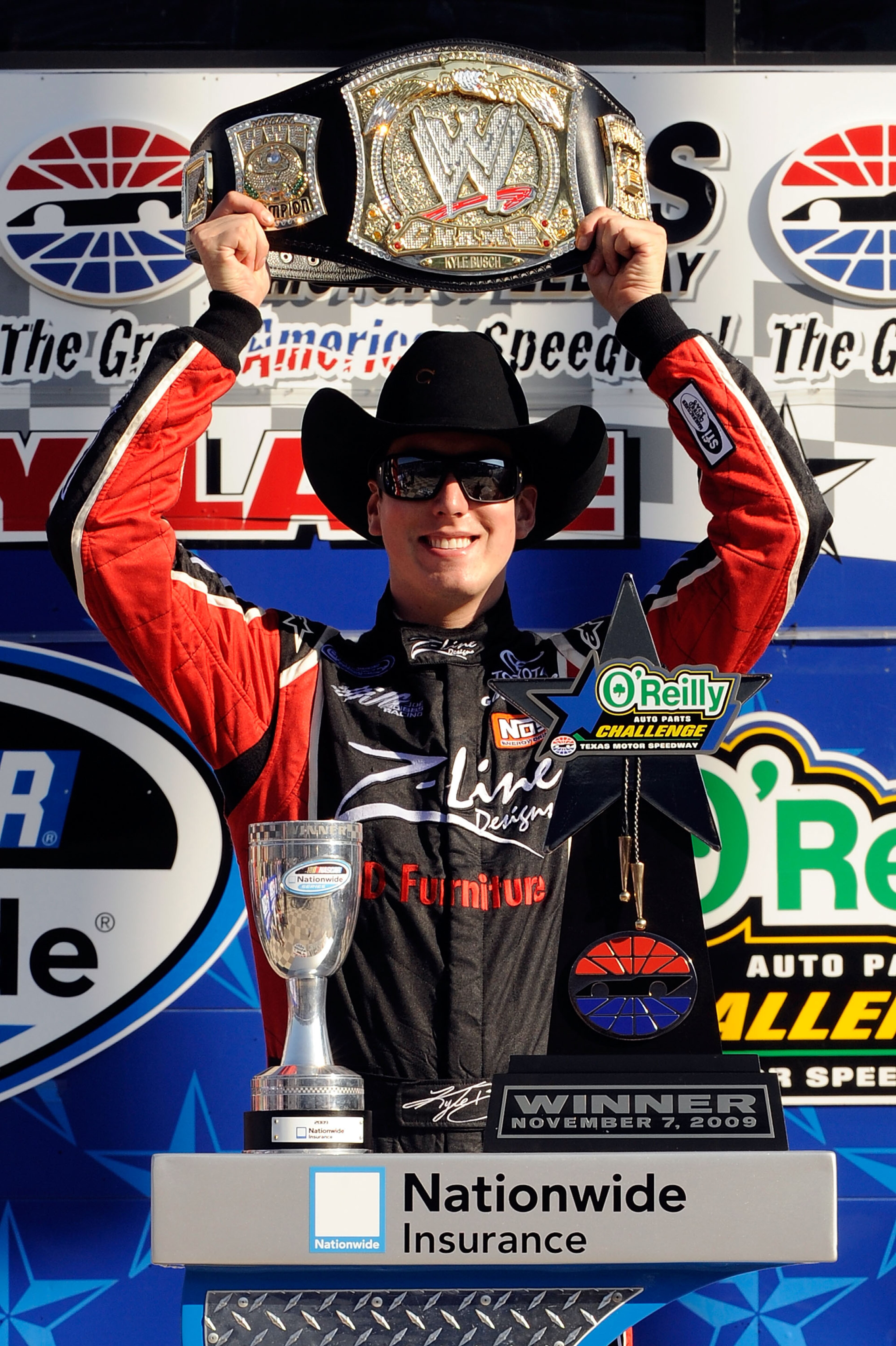FORT WORTH, TX - NOVEMBER 07:  Kyle Busch, driver of the #18 Z-Line Designs/WWE Smackdown Toyota,  hoist a replica of the WWE world championship belt on victory lane after winning the NASCAR Nationwide Series O'Reilly Challenge at Texas Motor Speedway on 
