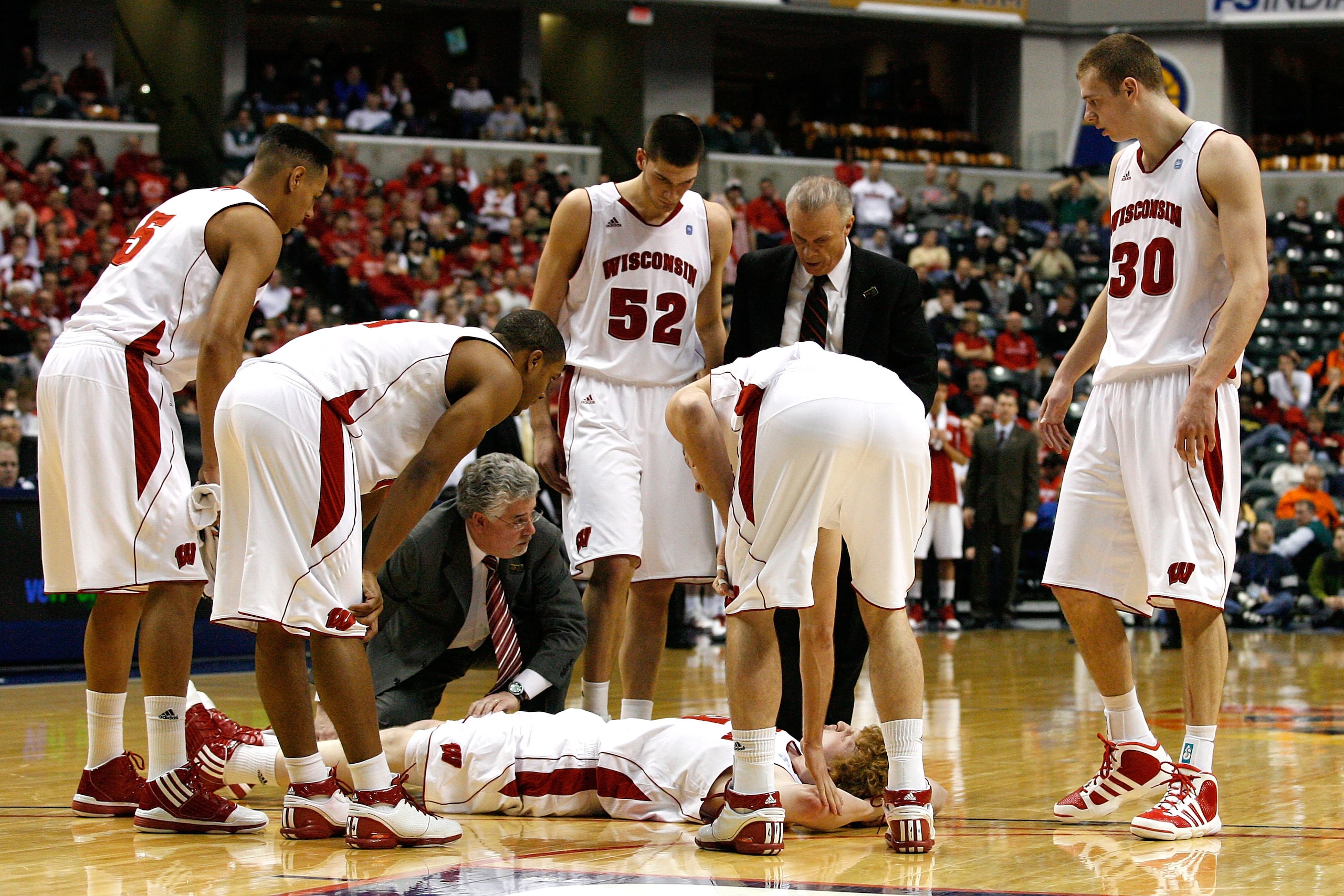 INDIANAPOLIS, IN - MARCH 11:  Mike Bruesewitz #31 of the Wisconsin Badgers is attended to by head coach Bo Ryan and the Badgers medical staff after he was hurt in the second half during the quarterfinals of the 2011 Big Ten Men's Basketball Tournament at 
