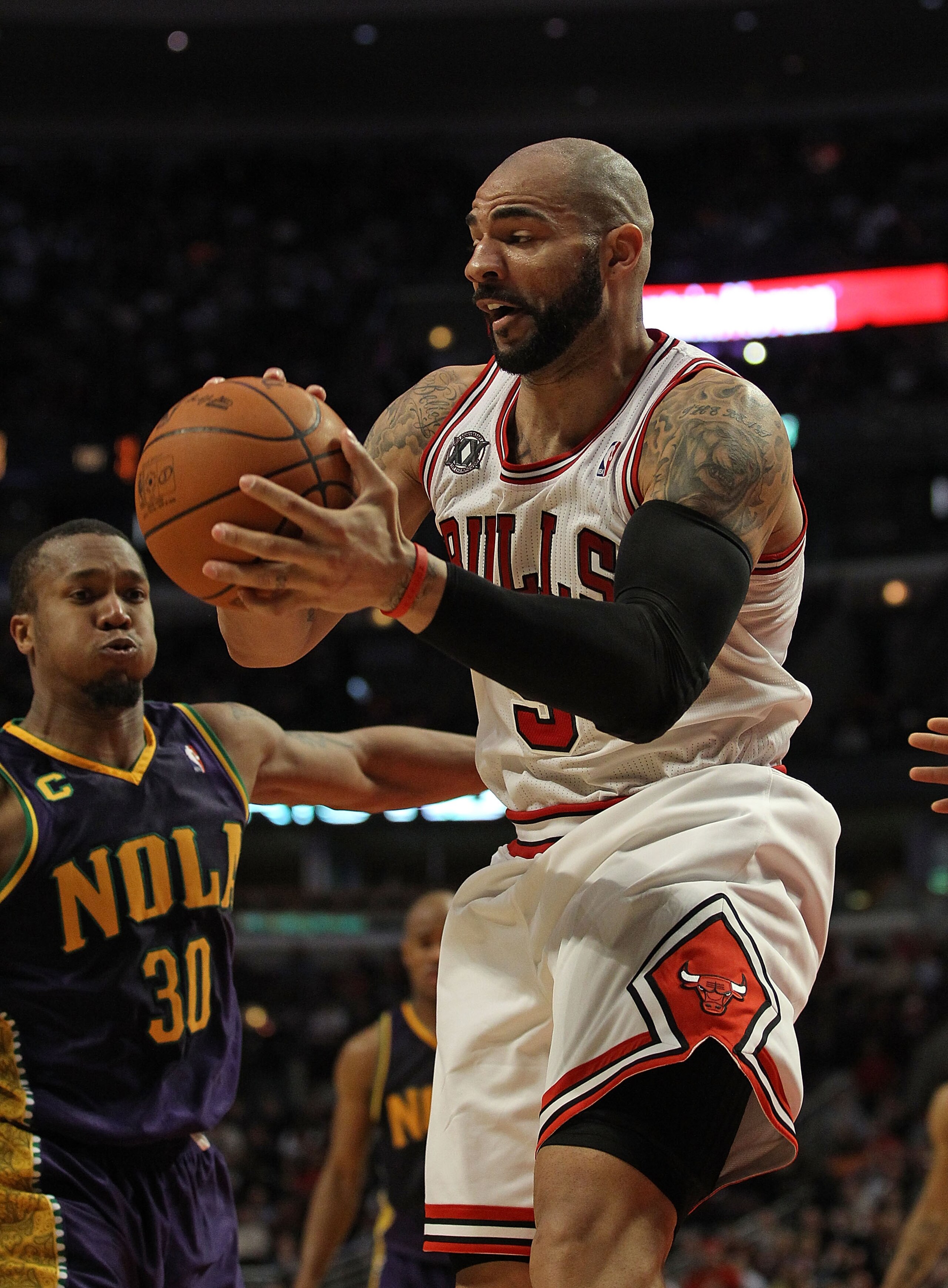 CHICAGO, IL - MARCH 07: Carlos Boozer #5 of the Chicago Bulls grabs a rebound next to David West #30 of the New Orleans Hornets at the United Center on March 7, 2011 in Chicago, Illinois. The Bulls defeated the Hornets 85-77. NOTE TO USER: User expressly