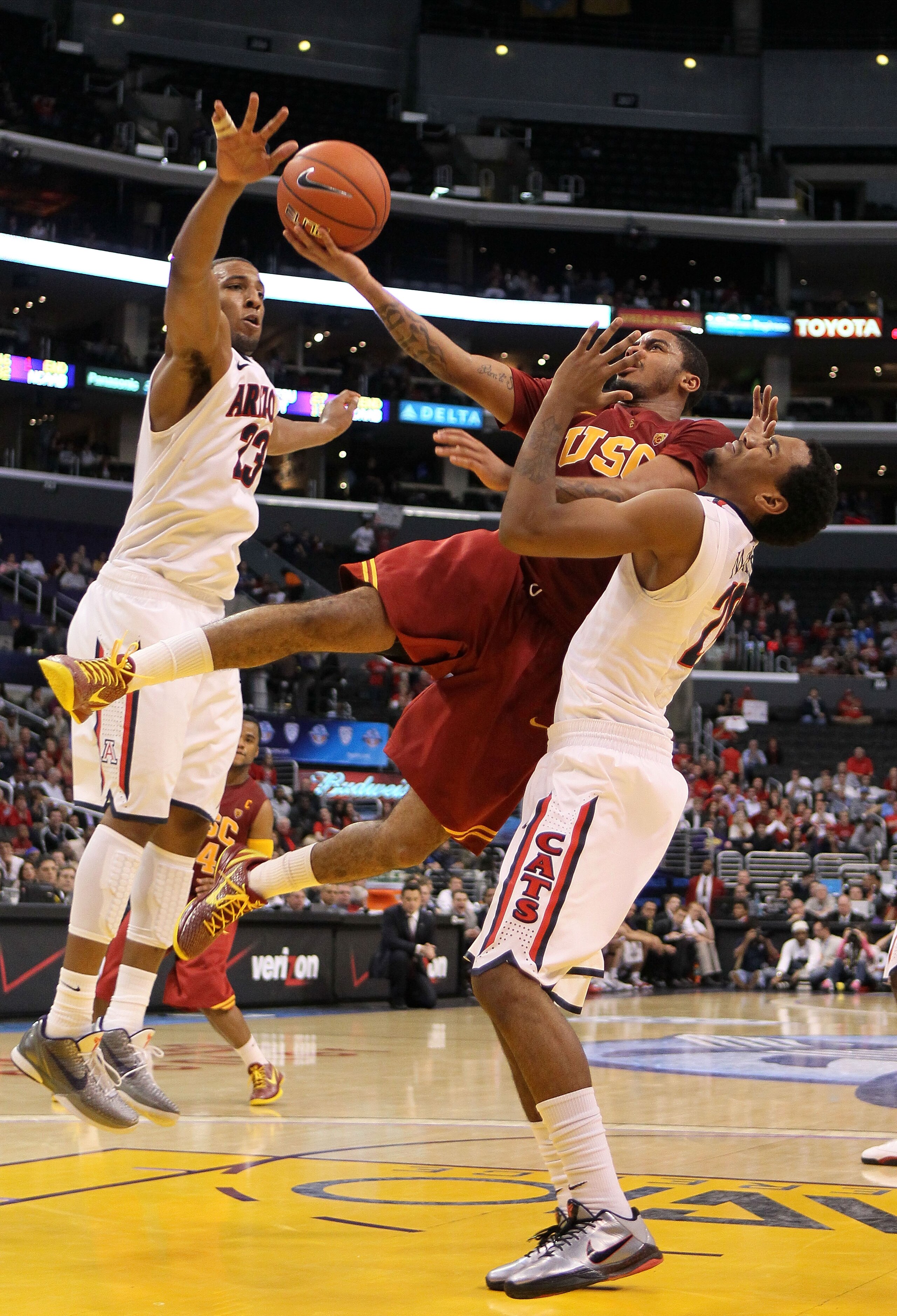 LOS ANGELES, CA - MARCH 11:  Jio Fontan #2 of the USC Trojans goes up for a shot against Derrick Williams #23 and Jordin Mayes #20 of the Arizona Wildcats in the second half in the semifinals of the 2011 Pacific Life Pac-10 Men's Basketball Tournament at