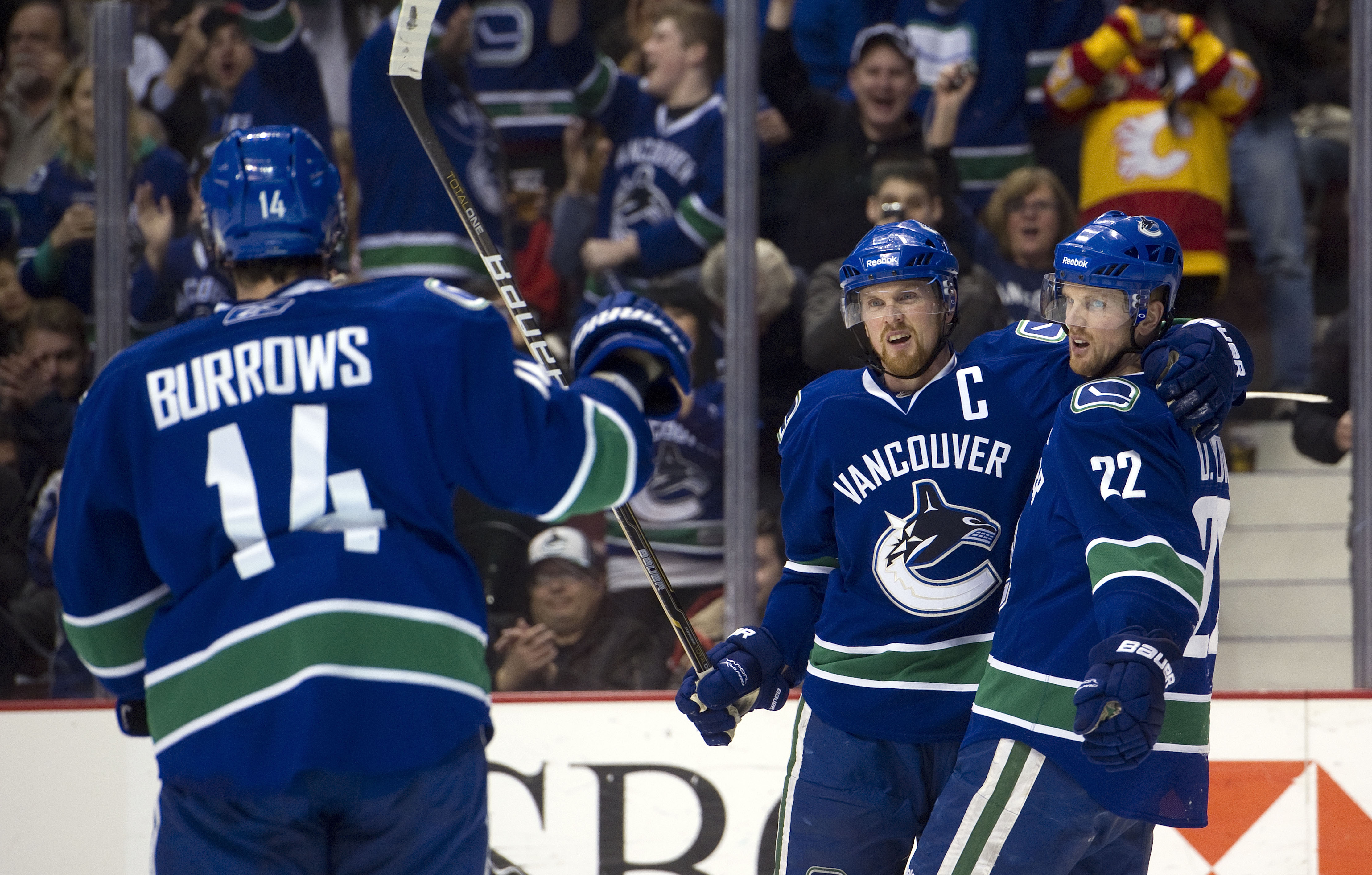 VANCOUVER, CANADA - JANUARY 5: Daniel Sedin #22 of the Vancouver Canucks celebrates with brother Henrik Sedin #33 and Alexandre Burrows #14 after scoring against the Calgary Flames during the second period in NHL action on January 05, 2011 at Rogers Arena
