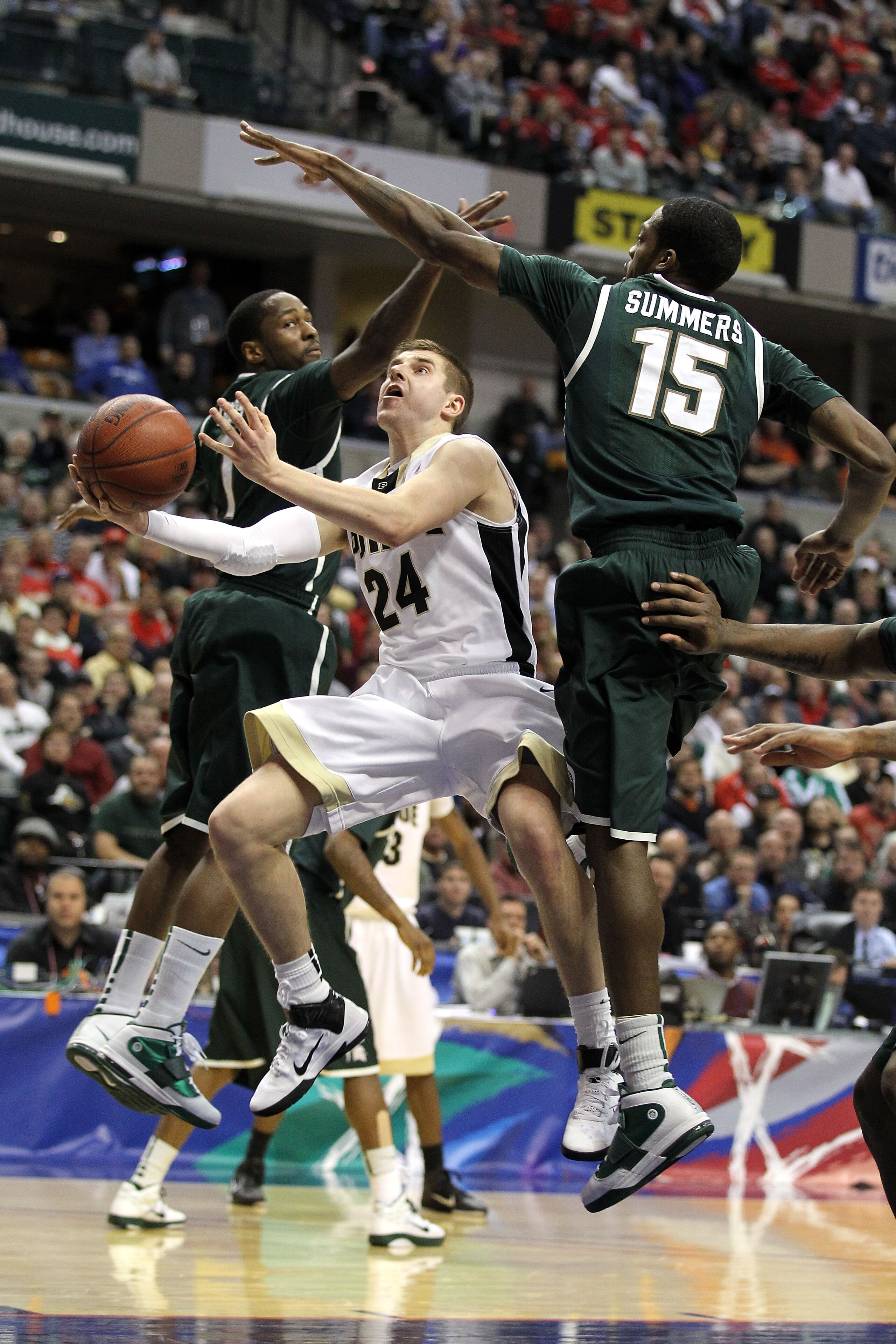 INDIANAPOLIS, IN - MARCH 11:  Ryne Smith #24 of the Purdue Boilermakers drives for a shot attempt against Durrell Summers #15 and Kalin Lucas #1 of the Michigan State Spartans during the quarterfinals of the 2011 Big Ten Men's Basketball Tournament at Con