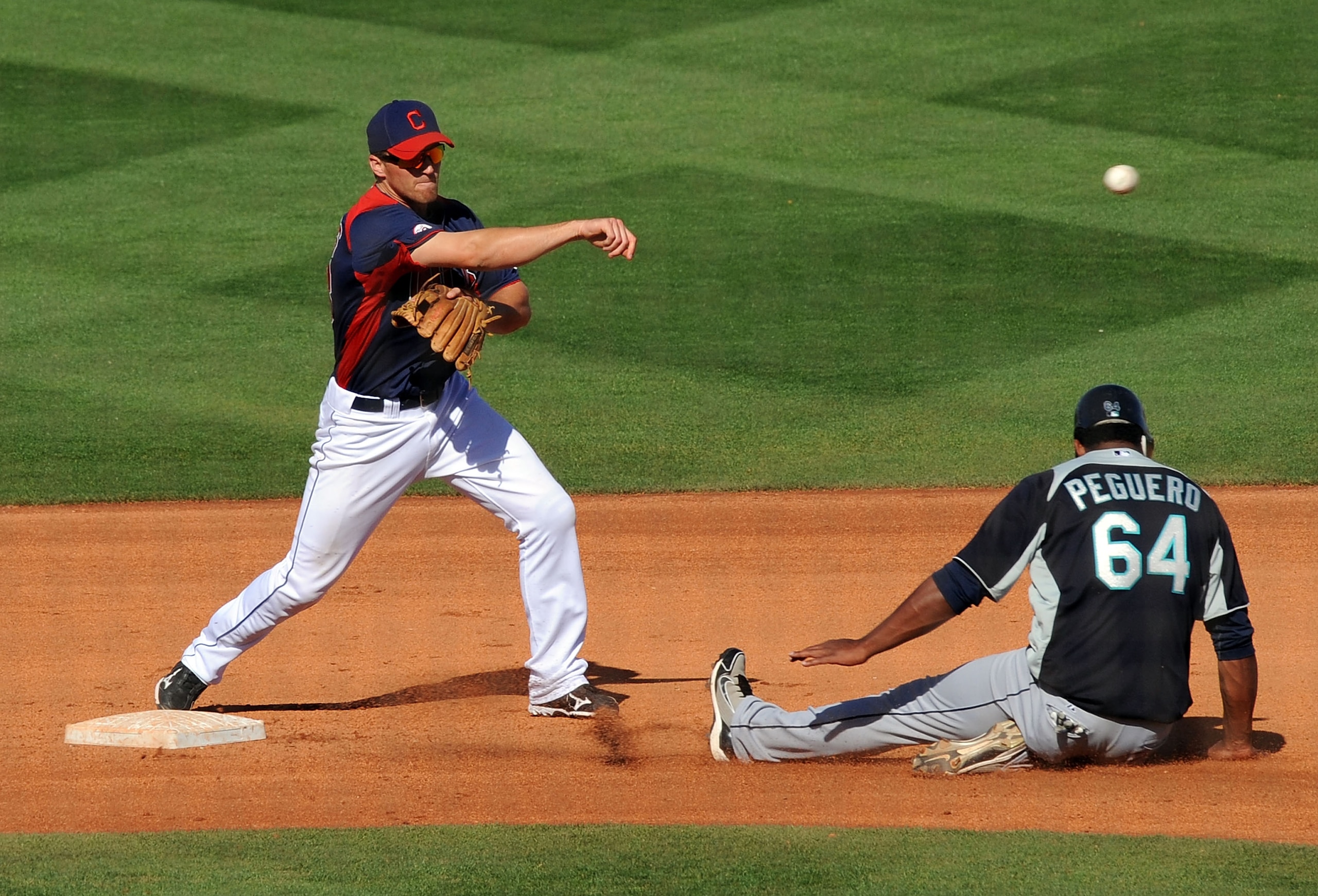 GOODYEAR, AZ - MARCH 11:  Cord Phelps #73 of the Cleveland Indians turns a double play over the top of a sliding Carlos Peguero #64 of the Seattle Mariners at Goodyear Ballpark on March 11, 2011 in Goodyear, Arizona.  (Photo by Norm Hall/Getty Images)