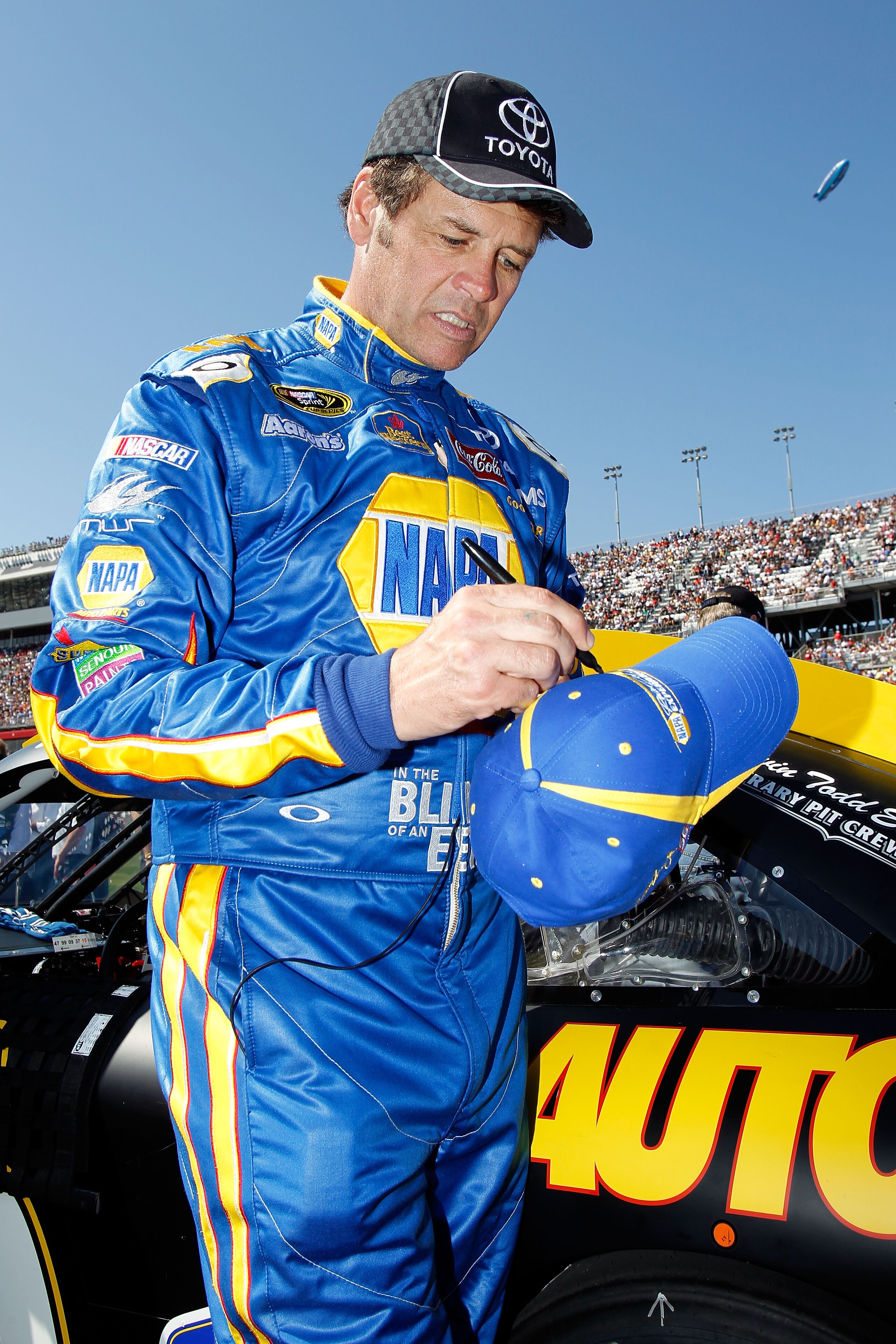 DAYTONA BEACH, FL - FEBRUARY 20:  Michael Waltrip, driver of the #15 NAPA Auto Parts Toyota, signs an autograph on the grid prior to the NASCAR Sprint Cup Series Daytona 500 at Daytona International Speedway on February 20, 2011 in Daytona Beach, Florida.