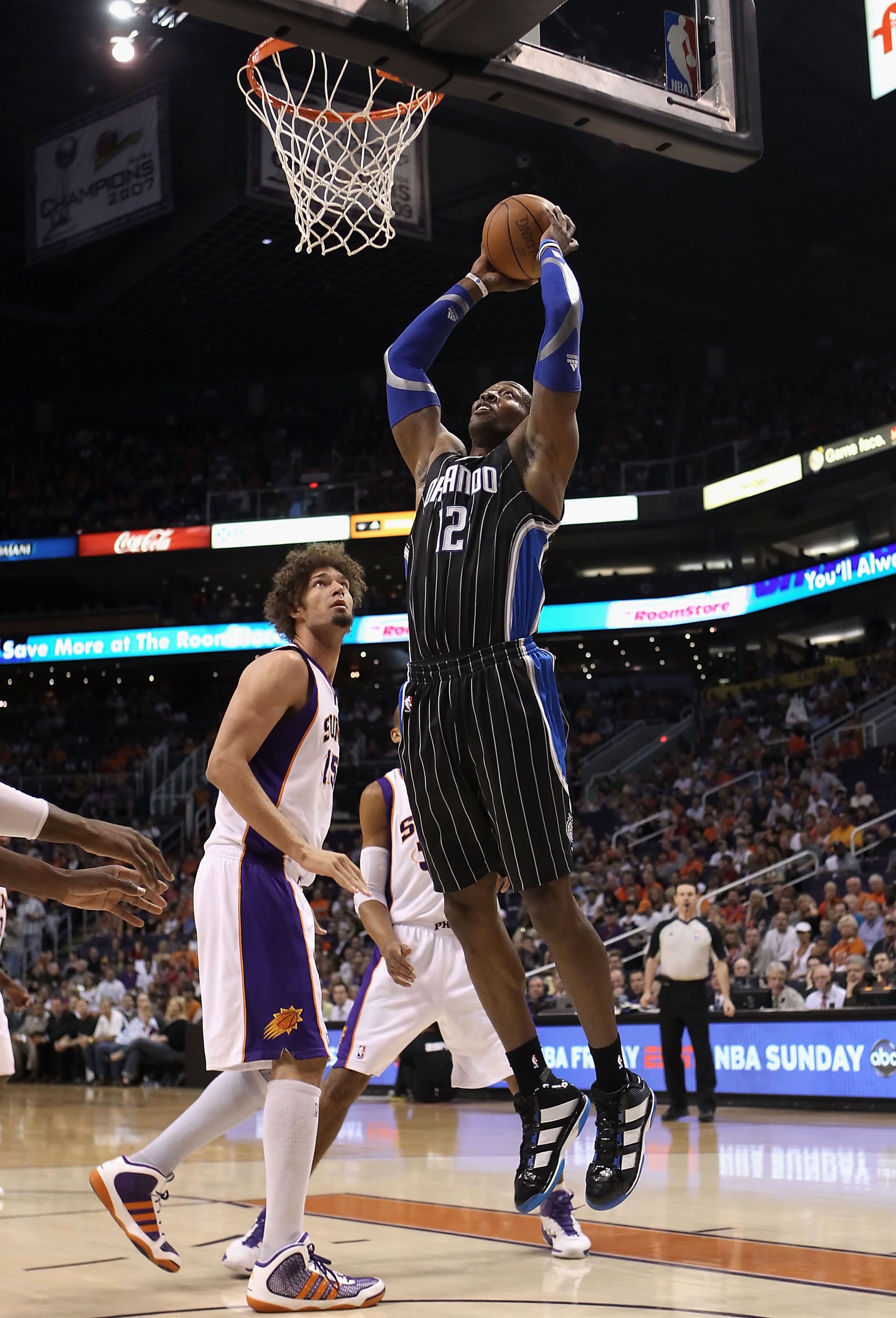 PHOENIX, AZ - MARCH 13:  Dwight Howard #12 of the Orlando Magic slam dunks the ball over Robin Lopez #15 of the Phoenix Suns during the NBA game at US Airways Center on March 13, 2011 in Phoenix, Arizona.  NOTE TO USER: User expressly acknowledges and agr