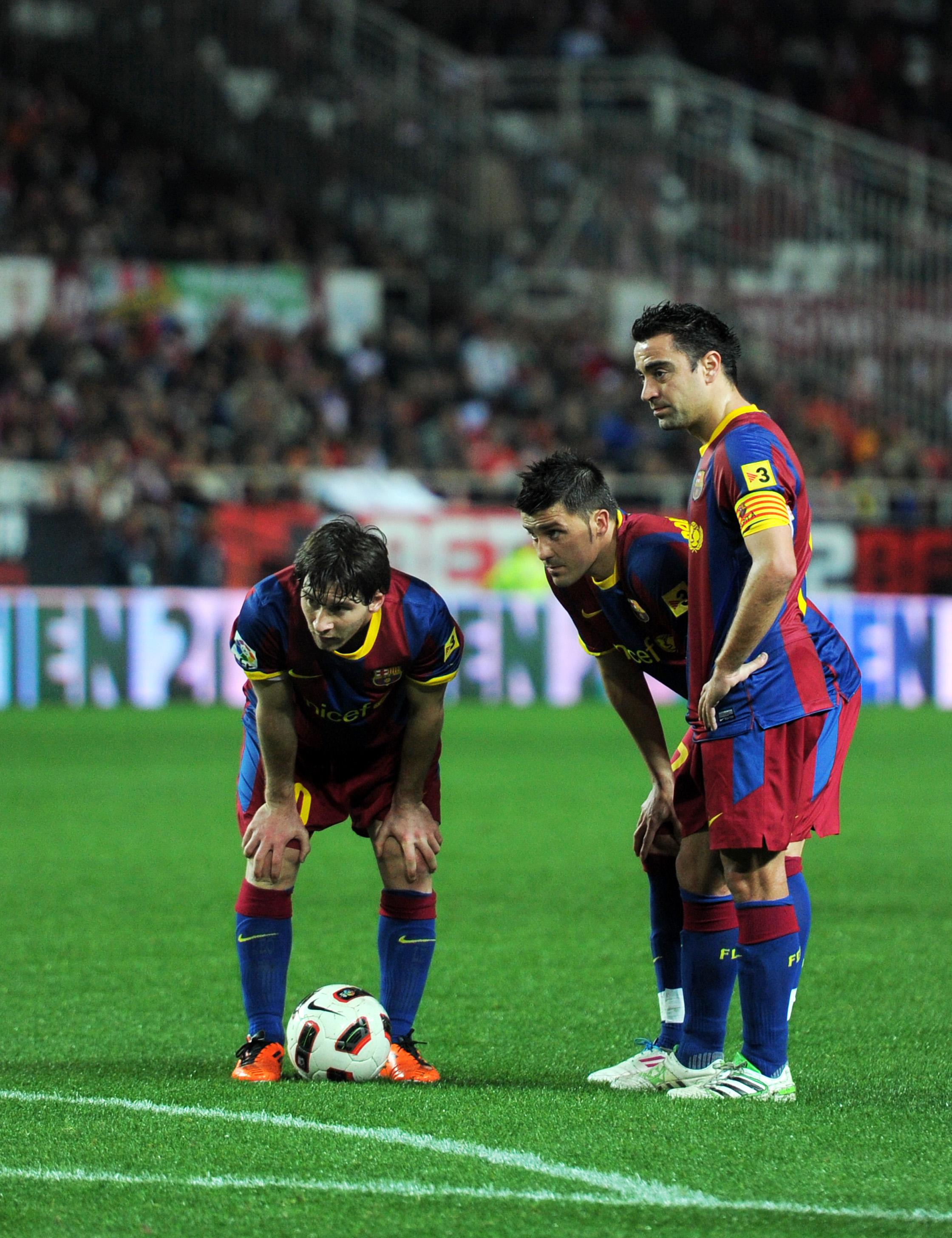 SEVILLE, SPAIN - MARCH 13:  Lionel Messi (L), David Villa (C) and Xavi Hernandez of Barcelona line up a free kick during the la Liga match between Sevilla and Barcelona at Estadio Ramon Sanchez Pizjuan on March 13, 2011 in Seville, Spain.  (Photo by Jaspe