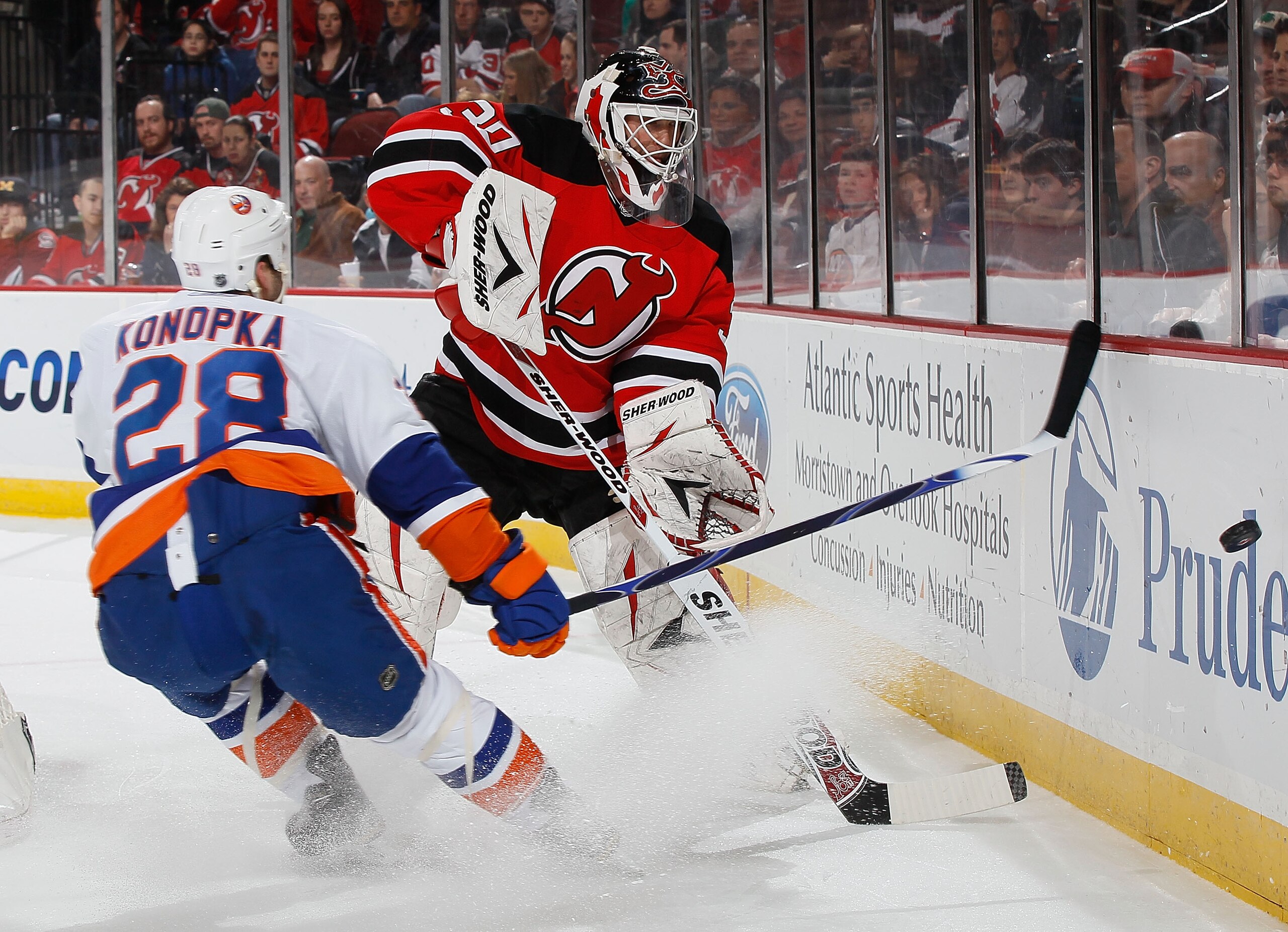 NEWARK, NJ - MARCH 12:  Goaltender Martin Brodeur #30 of the New Jersey Devils clears the puck behind the net against Zenon Konopka #28 of the New York Islanders on March 12, 2011 at the Prudential Center in Newark, New Jersey.  (Photo by Mike Stobe/Getty