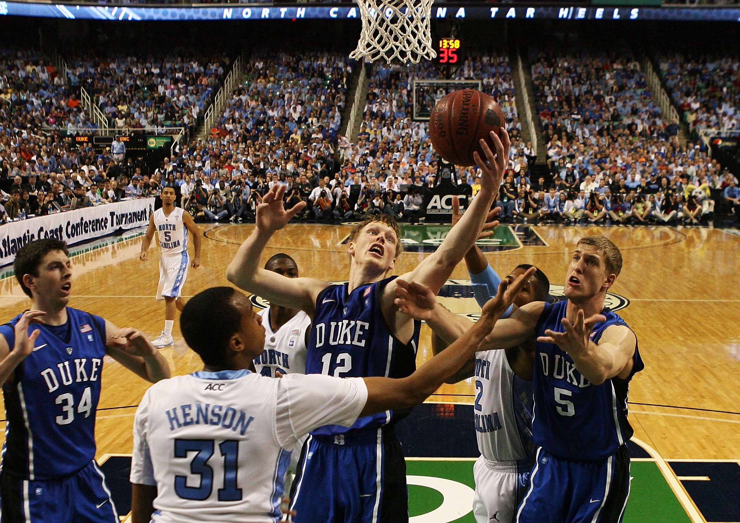 GREENSBORO, NC - MARCH 13:  Kyle Singler #12 and Mason Plumlee #5 of the Duke Blue Devils rebound against John Henson #31 of the North Carolina Tar Heels during the first half in the championship game of the 2011 ACC men's basketball tournament at the Gre