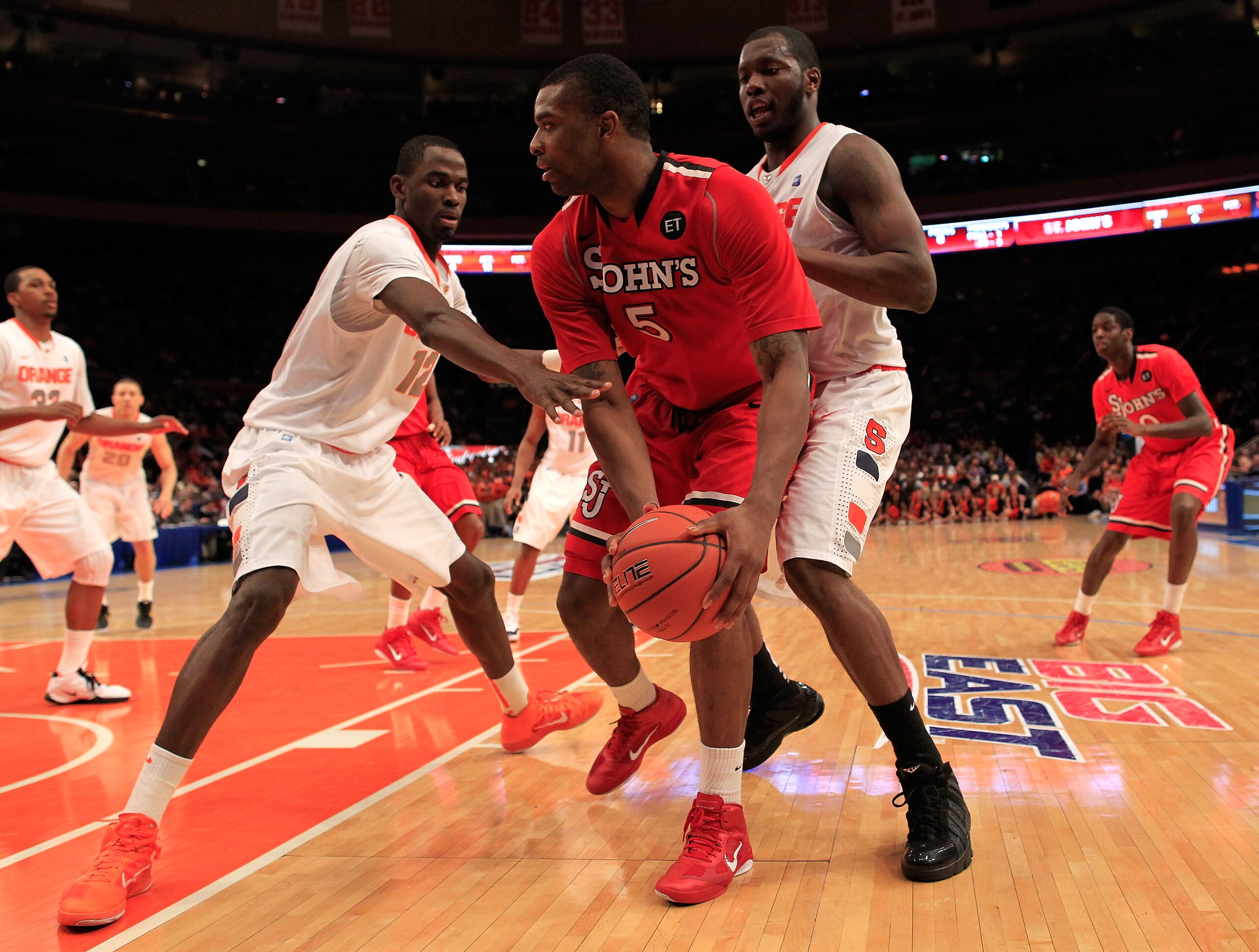NEW YORK, NY - MARCH 10: Sean Evans #5 of the St. John's Red Storm looks to pass against Baye Moussa Keita #12 and Rick Jackson #00 of the Syracuse Orange during the quarterfinals of the 2011 Big East Men's Basketball Tournament presented by American Eagl