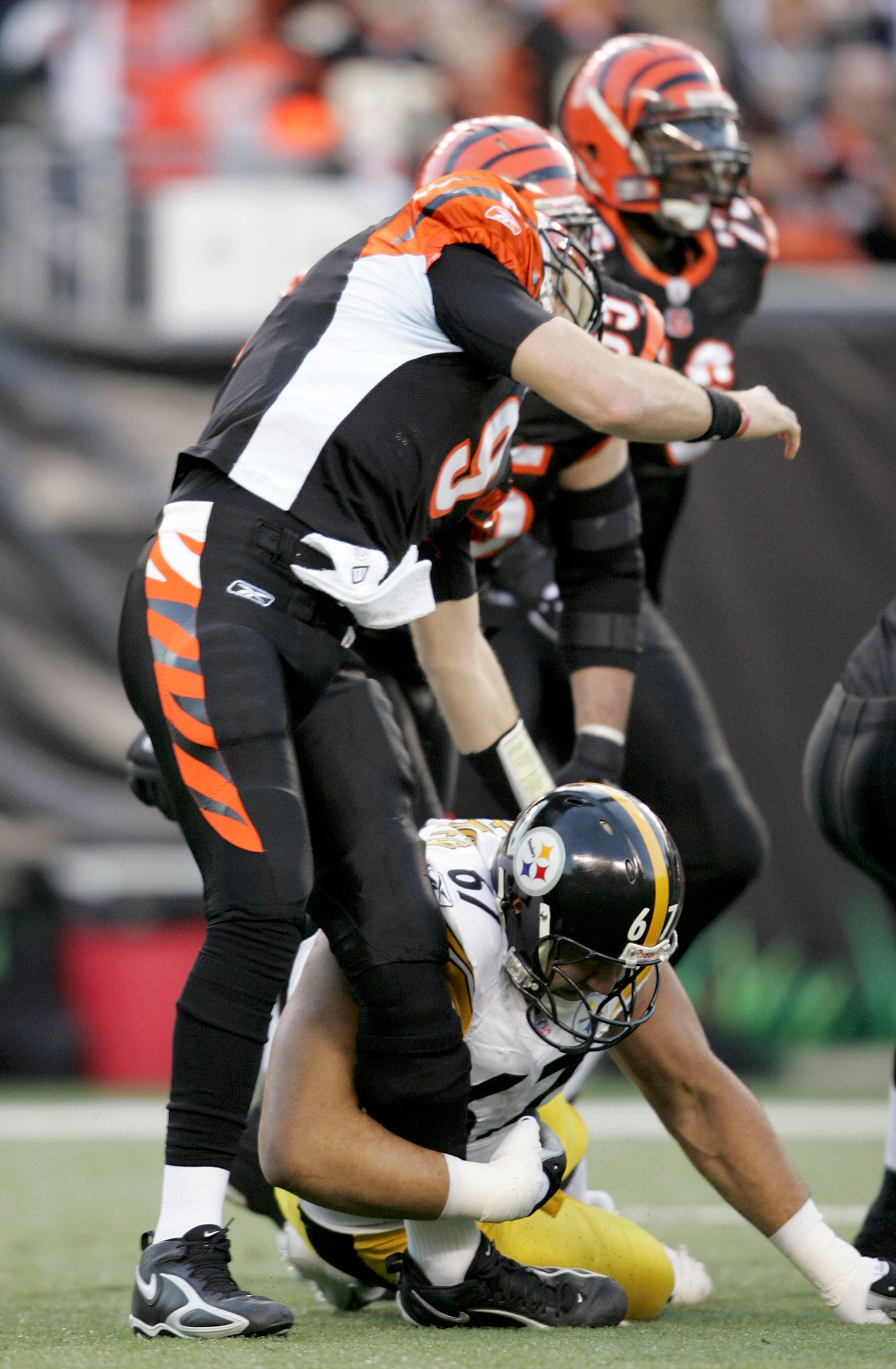 CINCINNATI - JANUARY 8:  Quarterback Carson Palmer #9 of the Cincinnati Bengals is hit in the knee by Kimo von Oelhoffen #67 of the Pittsburgh Steelers on the first drive of the AFC Wild Card Playoff Game at Paul Brown Stadium on January 8, 2006 in Cincin