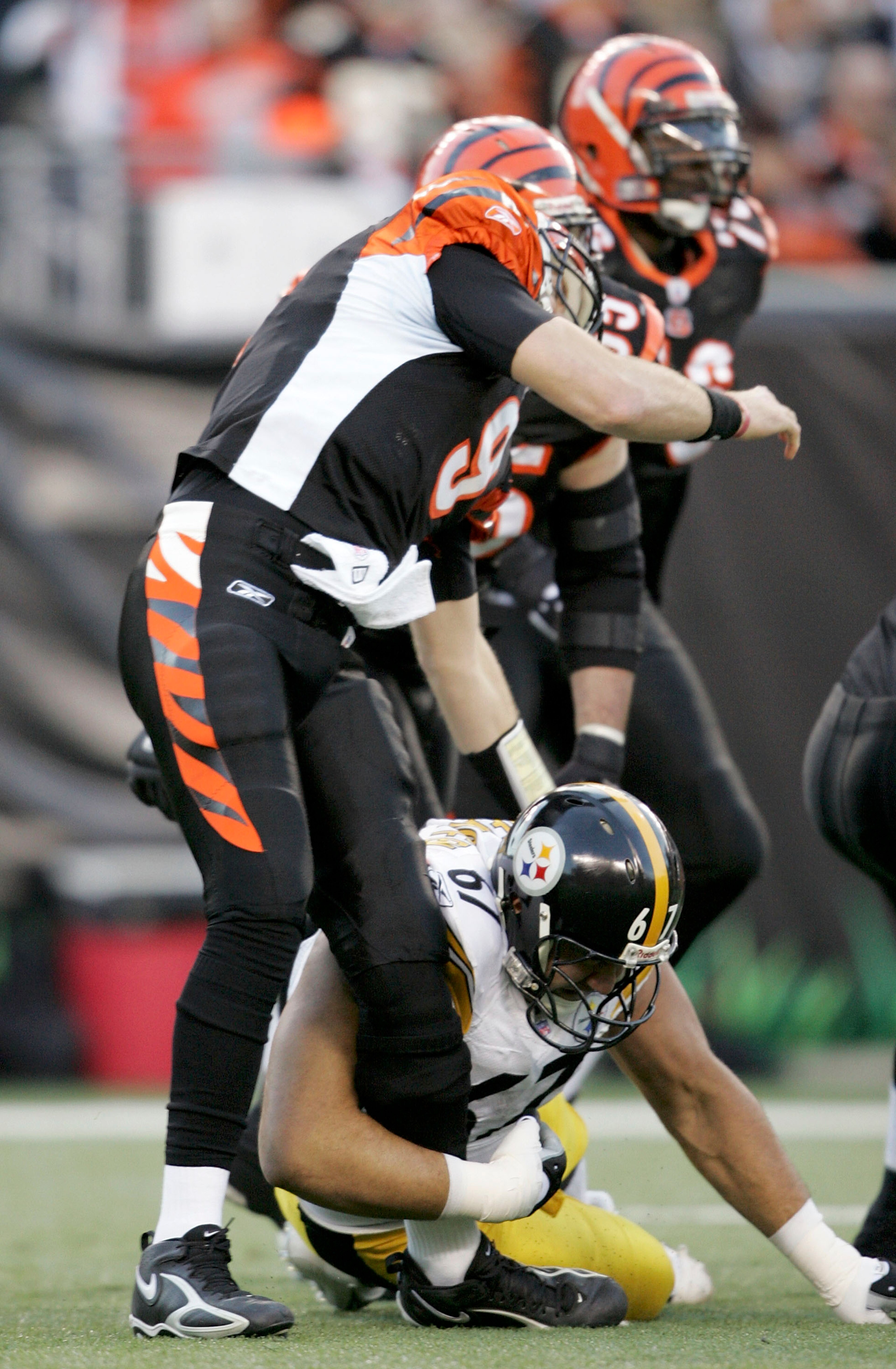CINCINNATI - JANUARY 8:  Quarterback Carson Palmer #9 of the Cincinnati Bengals is hit in the knee by Kimo von Oelhoffen #67 of the Pittsburgh Steelers on the first drive of the AFC Wild Card Playoff Game at Paul Brown Stadium on January 8, 2006 in Cincin