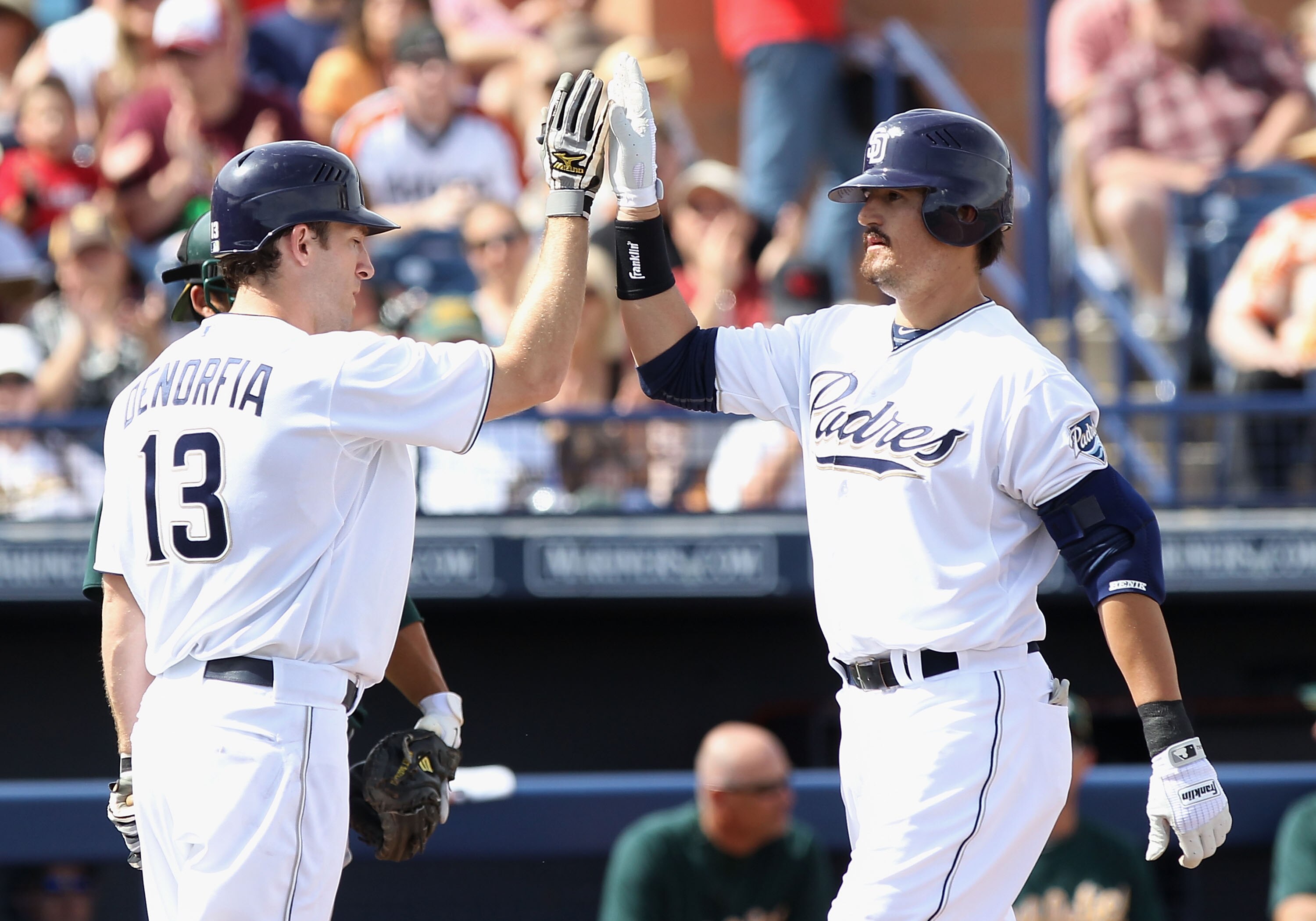 PEORIA, AZ - MARCH 06:  Jorge Cantu #32 of the San Diego Padres high fives teammate Chris Denorfia #13 after Cantu hit a 2 run home run against the Oakland Athletics during the first inning of the spring training game at Peoria Stadium on March 6, 2011 in