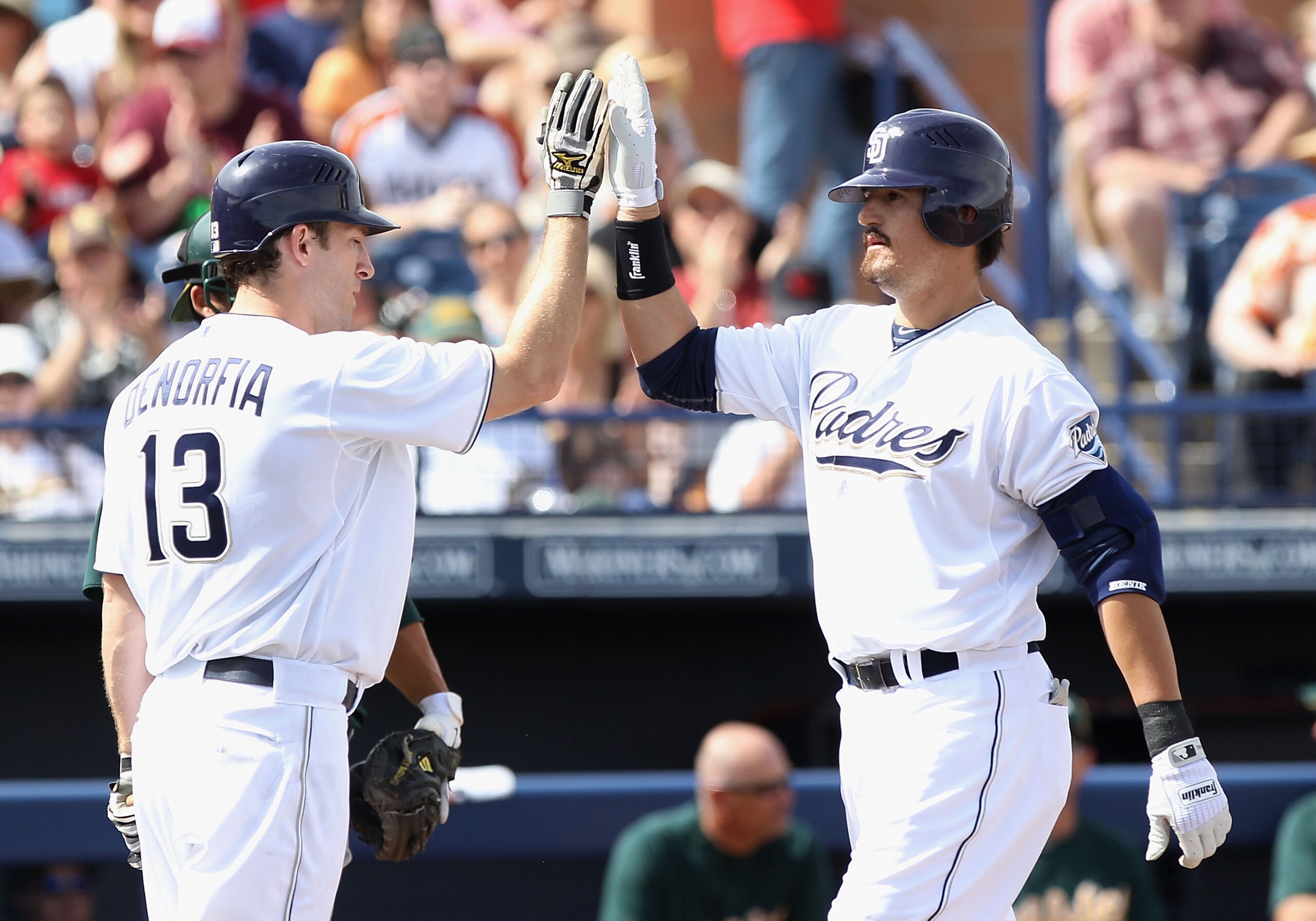 PEORIA, AZ - MARCH 06:  Jorge Cantu #32 of the San Diego Padres high fives teammate Chris Denorfia #13 after Cantu hit a 2 run home run against the Oakland Athletics during the first inning of the spring training game at Peoria Stadium on March 6, 2011 in