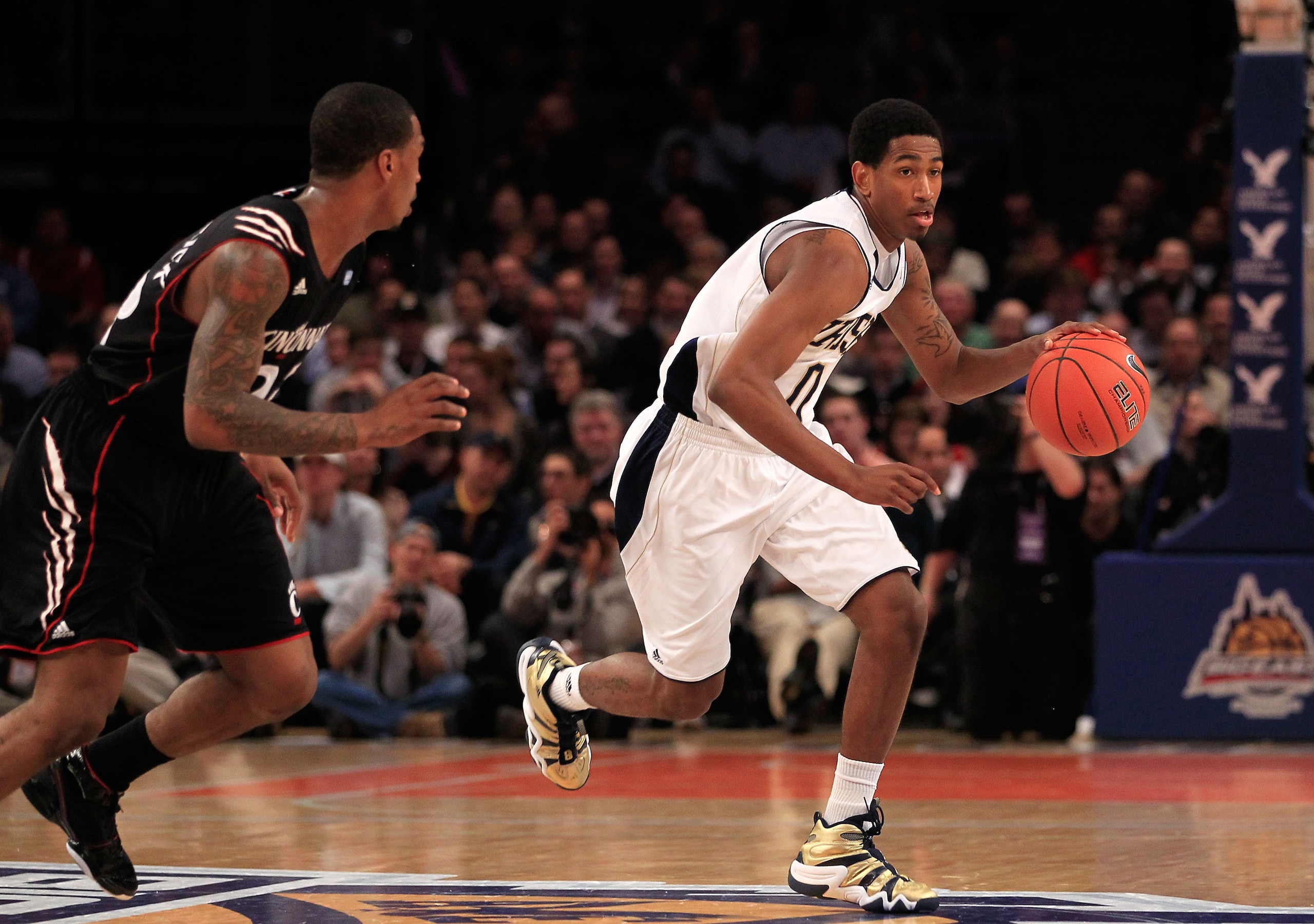 NEW YORK, NY - MARCH 10: Eric Atkins #0 of the Notre Dame Fighting Irish dribbles the ball up court against Sean Kilpatrick #23 of the Cincinnati Bearcats during the quarterfinals of the 2011 Big East Men's Basketball Tournament presented by American Eagl
