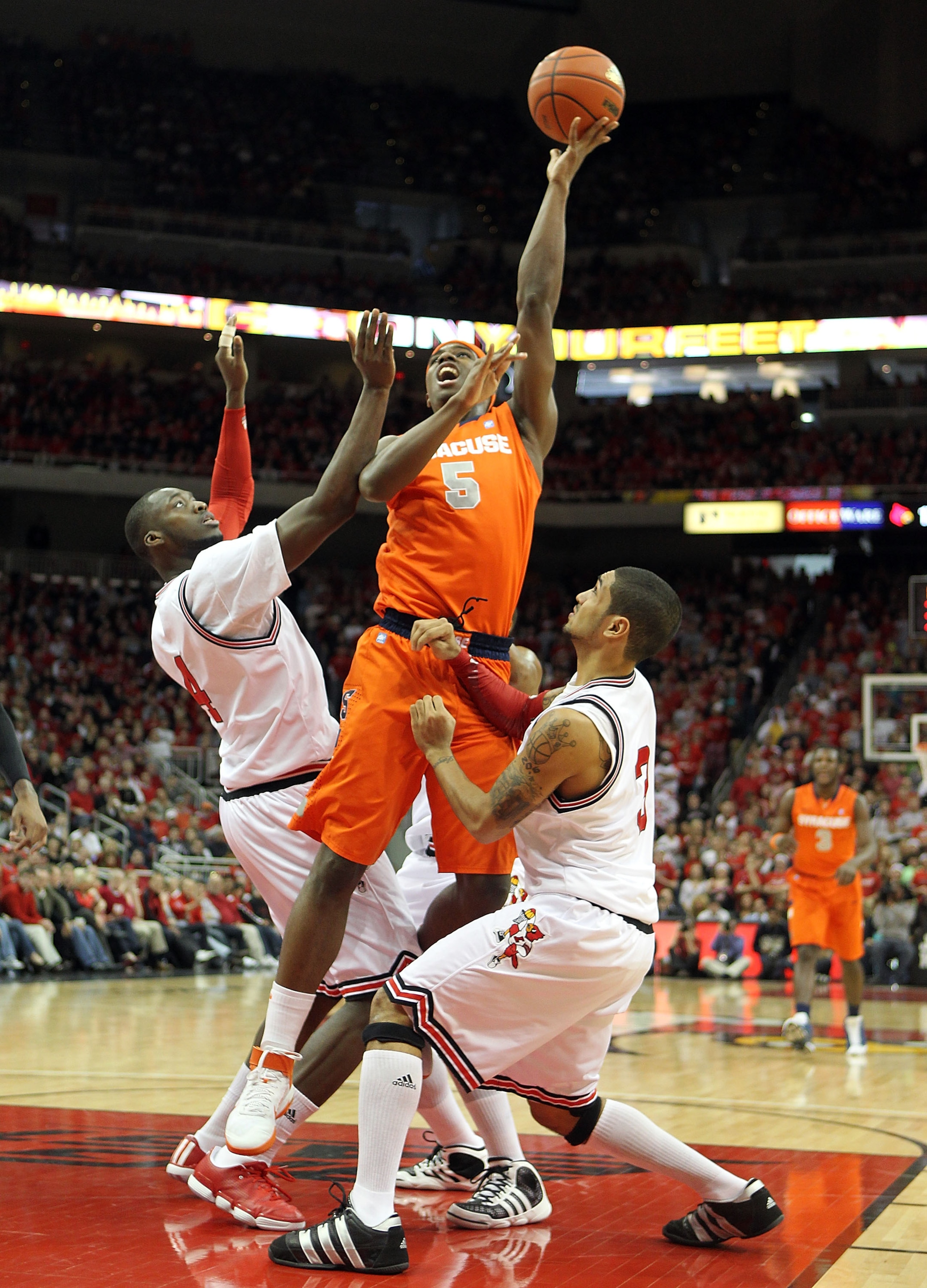 LOUISVILLE, KY - FEBRUARY 12:  C.J. Fair #5 of the Syracuse Orange shoots the ball while defended by Rakeem Buckles #4 and Peyton Siva #3 of the Louisville Cardinals during the Big East Conference game at the KFC Yum! Center on February 12, 2011 in Louisv