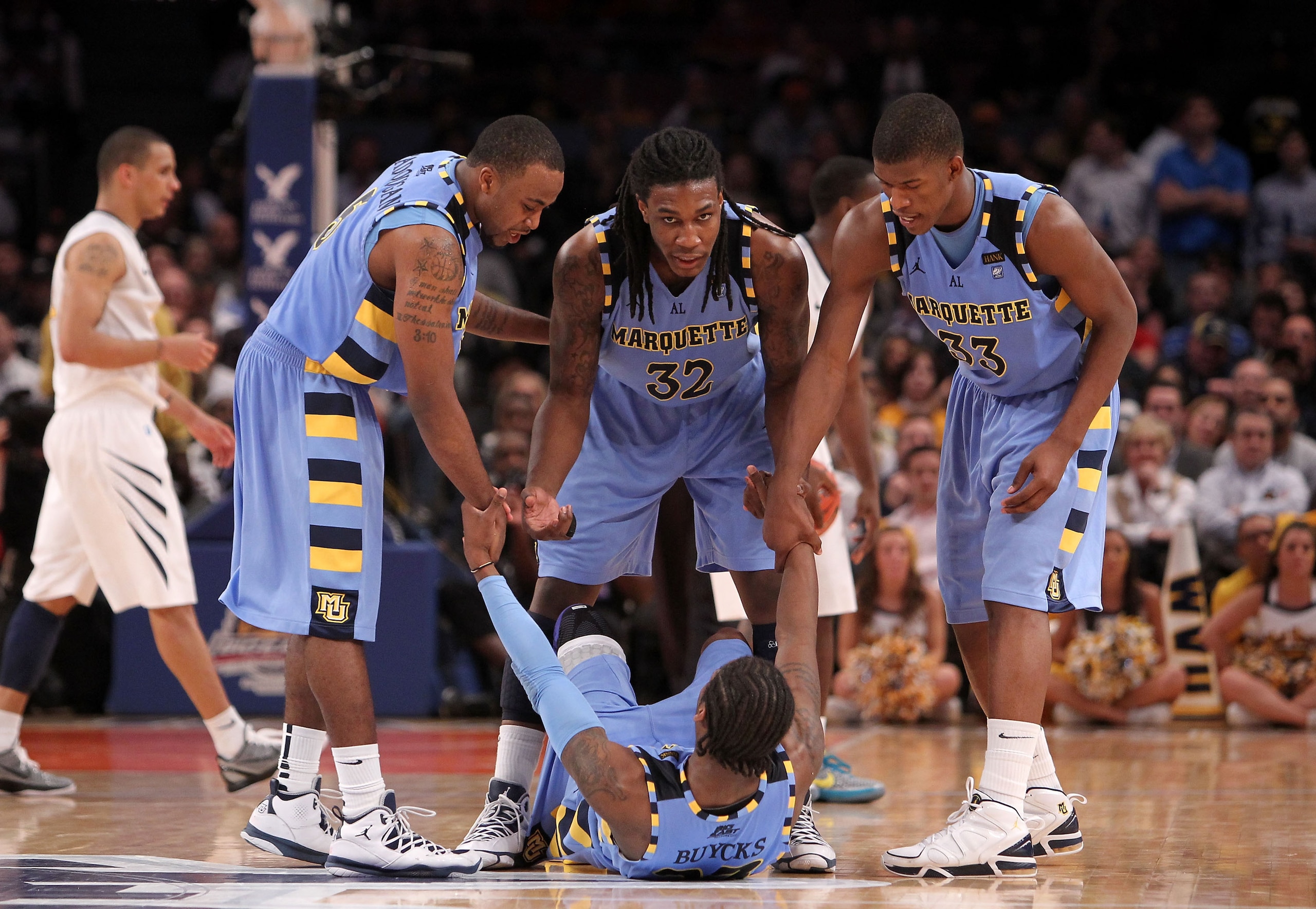 NEW YORK, NY - MARCH 09: Junior Cadougan #5, Jae Crowder #32 and Jimmy Butler #33 of the Marquette Golden Eagles help teammate Dwight Buycks #23 up off the court late in the second half during the second round of the 2011 Big East Men's Basketball Tournam