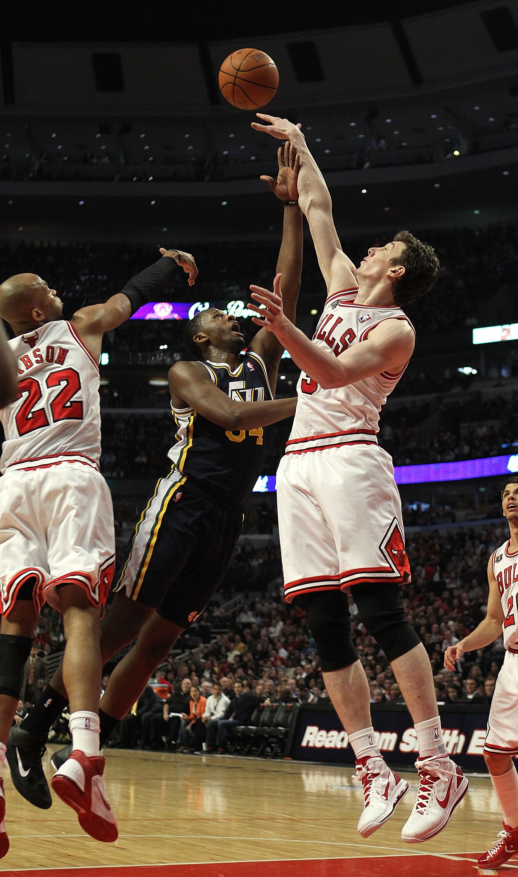 CHICAGO, IL - MARCH 12: Omer Asik #3 of the Chicago Bulls blocks a shot by C.J. Miles #34 of the Utah Jazz as Taj Gibson #22 also defends at the United Center on March 12, 2011 in Chicago, Illinois. NOTE TO USER: User expressly acknowledges and agrees tha