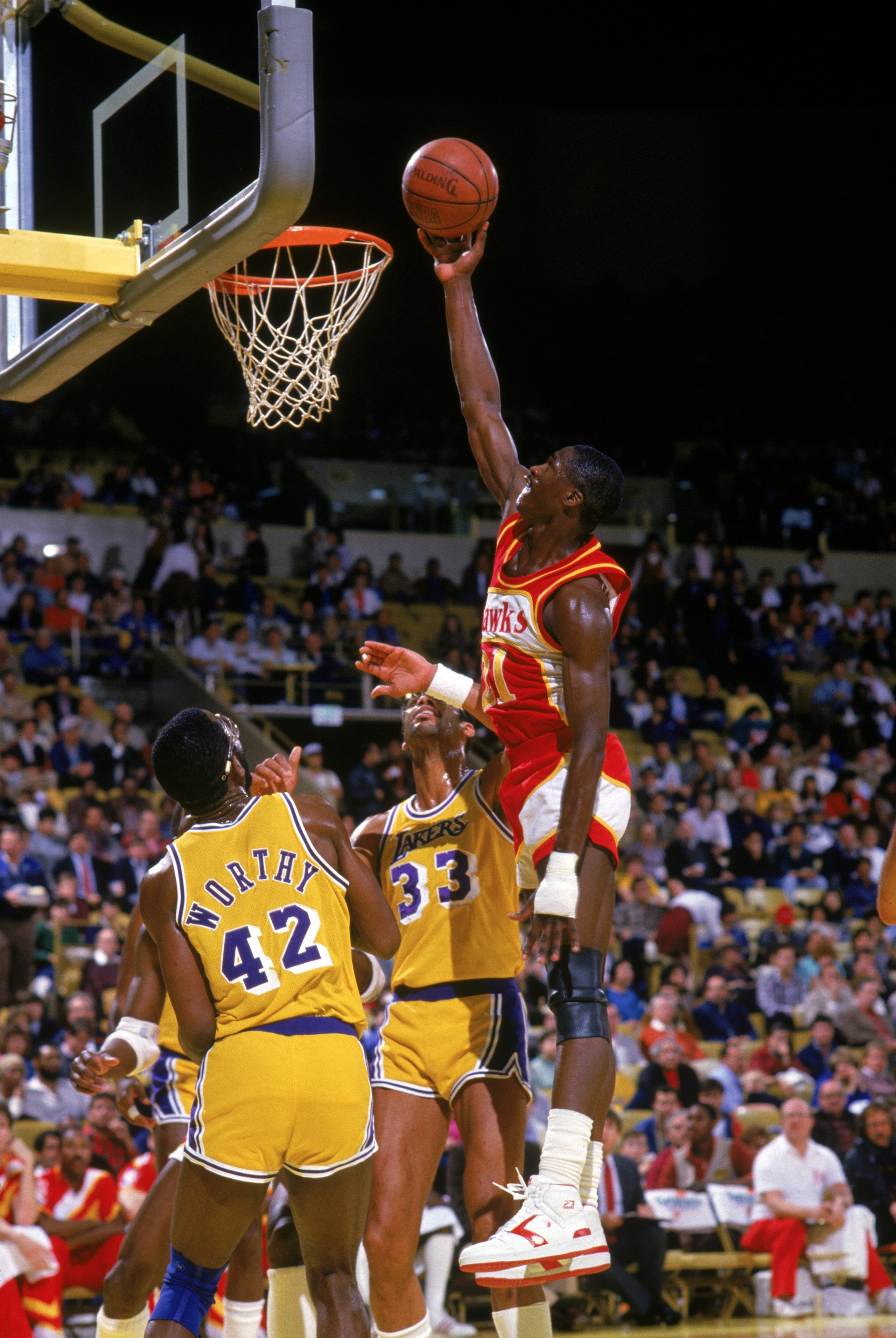 INGLEWOOD, CA - 1986:  Dominique Wilkins #21 of the Atlanta Hawks goes up for a layup against James Worthy #42 and Kareem Abdul-Jabbar #33 of the Los Angeles Lakers during a 1986 NBA season game at the Great Western Forum in Inglewood, California.   (Phot
