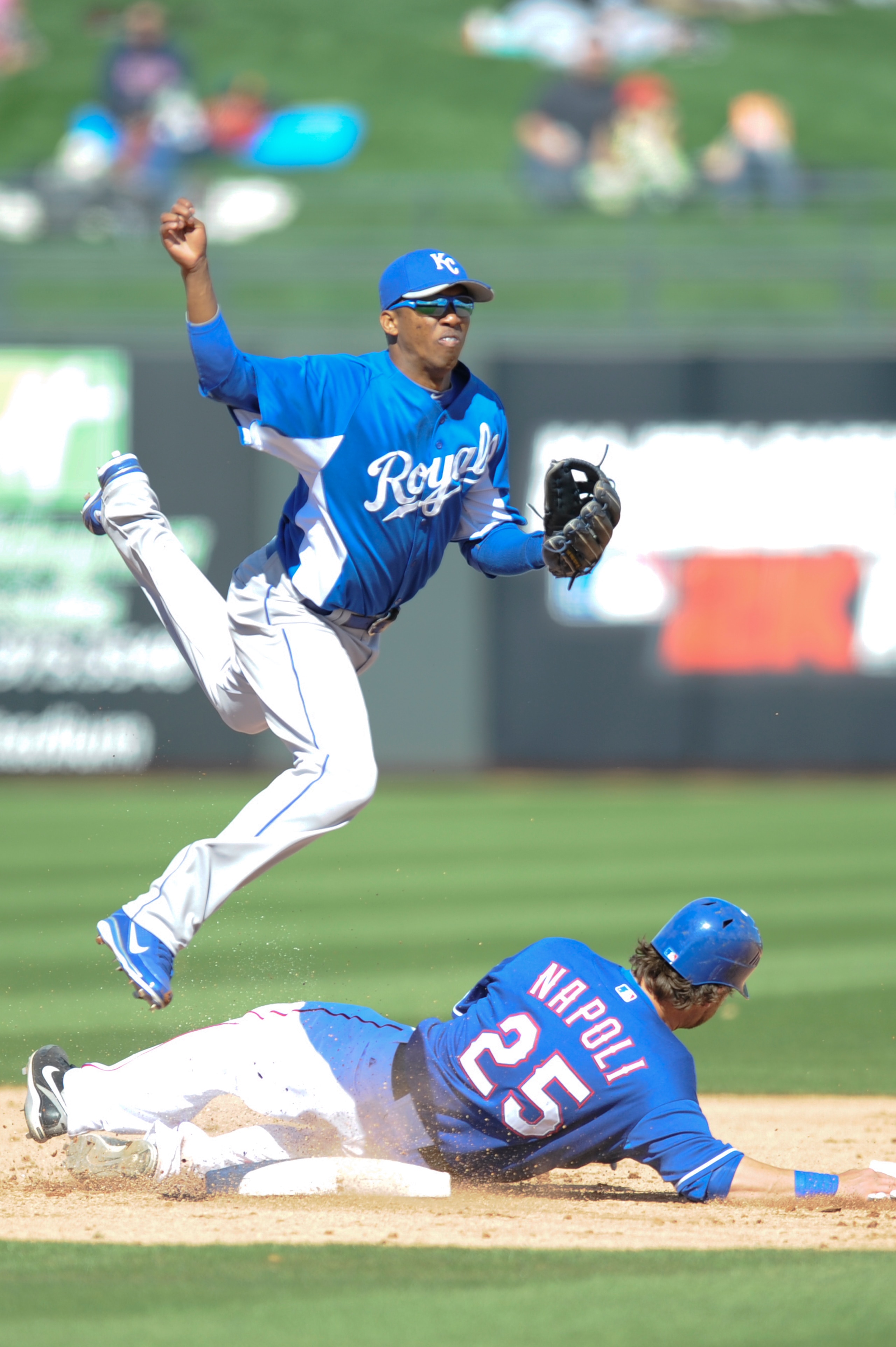 SURPISE, AZ - FEBRUARY 27: Alcides Escobar #2 of the Kansas City Royals attempts to complete a double play during a spring training game as Mike Napoli #25 of the Texas Rangers slides into him at Surprise Stadium on February 27, 2011 in Surprise, Arizona.