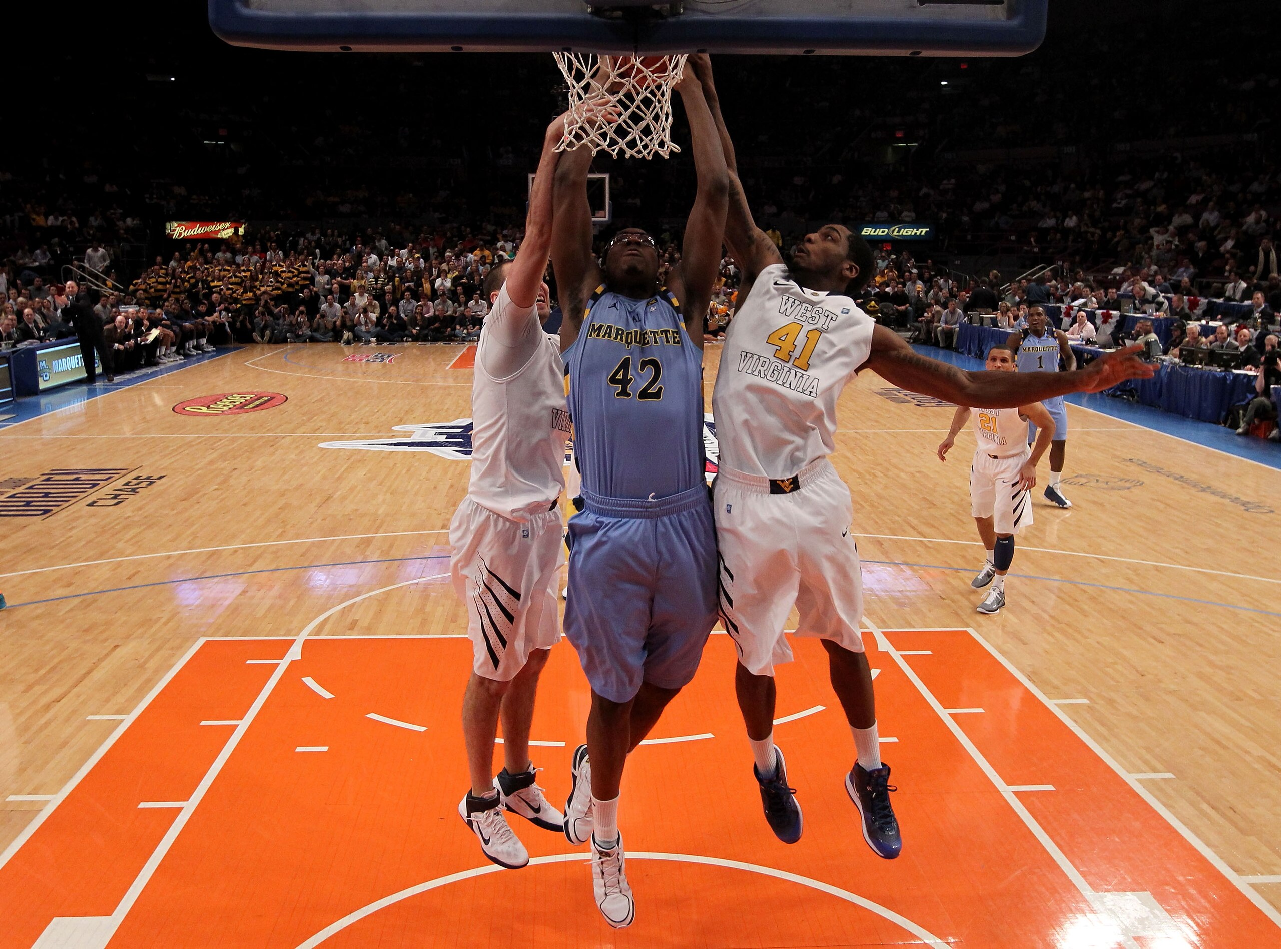 NEW YORK, NY - MARCH 09: Chris Otule #42 of the Marquette Golden Eagles goes up for a dunk against Cam Thoroughman #2 and John Flowers #41 of the West Virginia Mountaineers during the second round of the 2011 Big East Men's Basketball Tournament presented