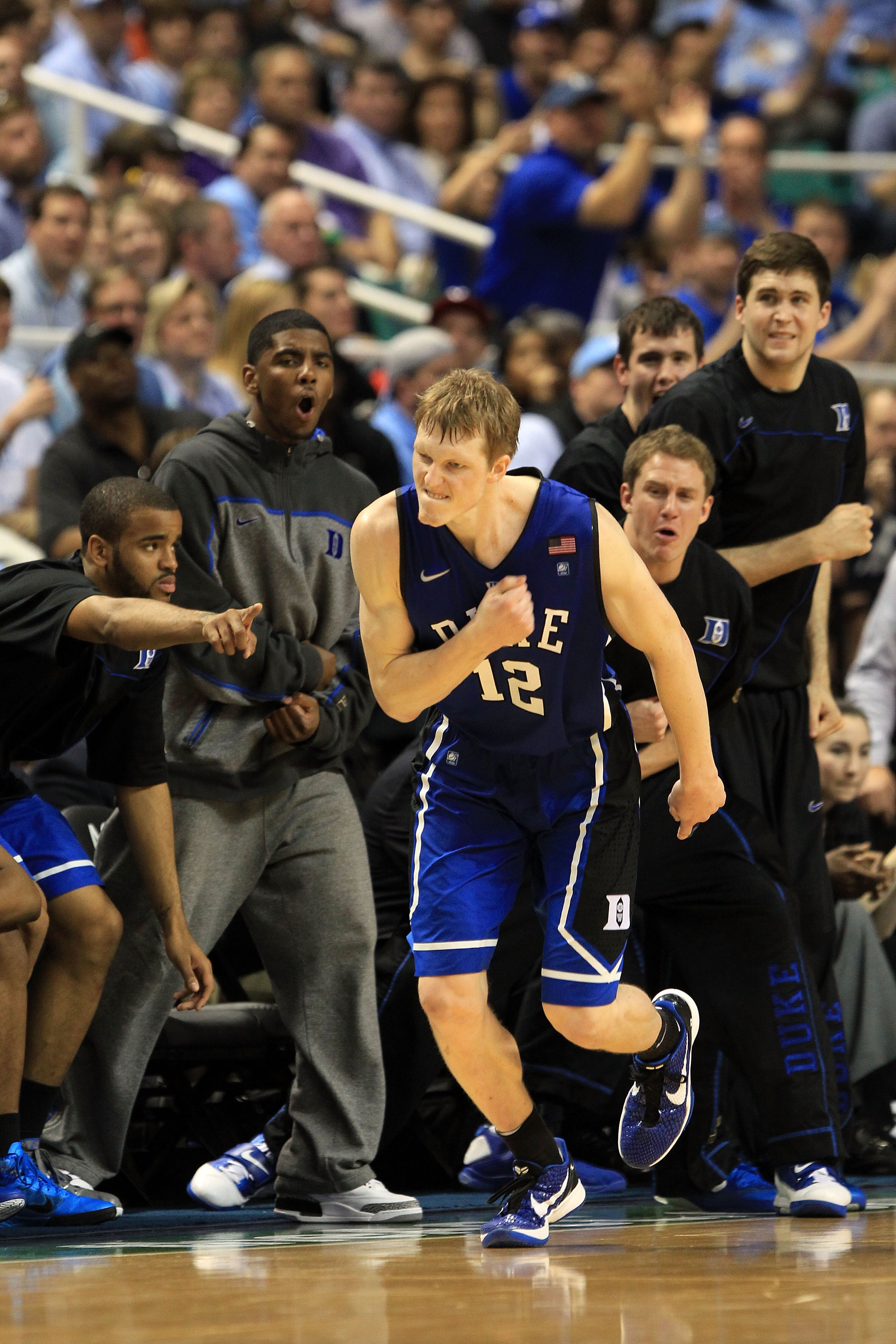 GREENSBORO, NC - MARCH 13:  Kyle Singler #12 of the Duke Blue Devils reacts as teammate Kyrie Irving #1 and the bench cheer him on during the second half of the game against the North Carolina Tar Heels in the championship game of the 2011 ACC men's baske