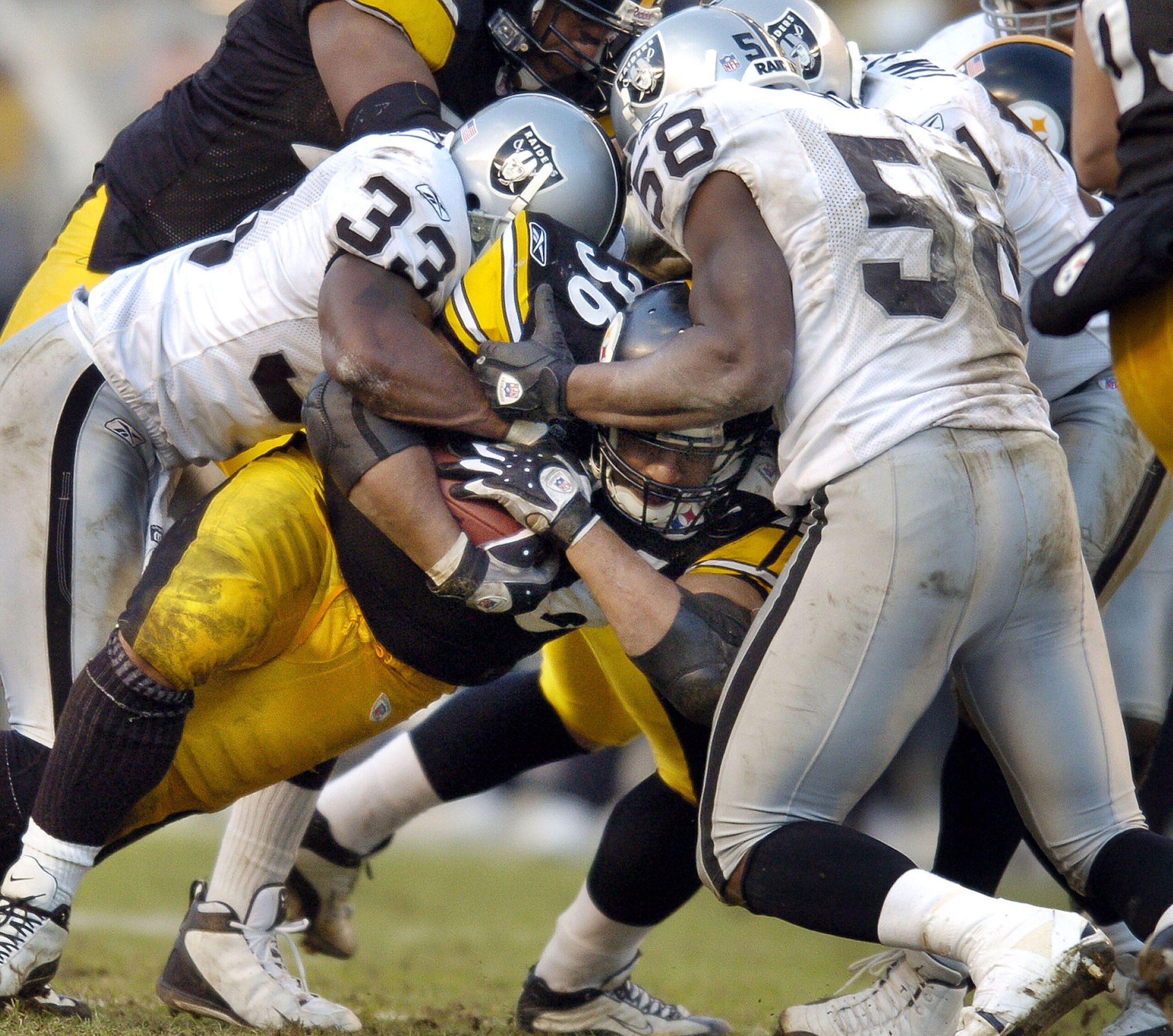 PITTSBURGH - DECEMBER 7:  Jerome Bettis #36 of the Pittsburgh Steelers works for extra yards after being hit by Anthony Dorsett #33 and Napoleon Harris #58 of the Oakland Raiders during the fourth quarter on December 7, 2003 at Heinz Field in Pittsburgh,