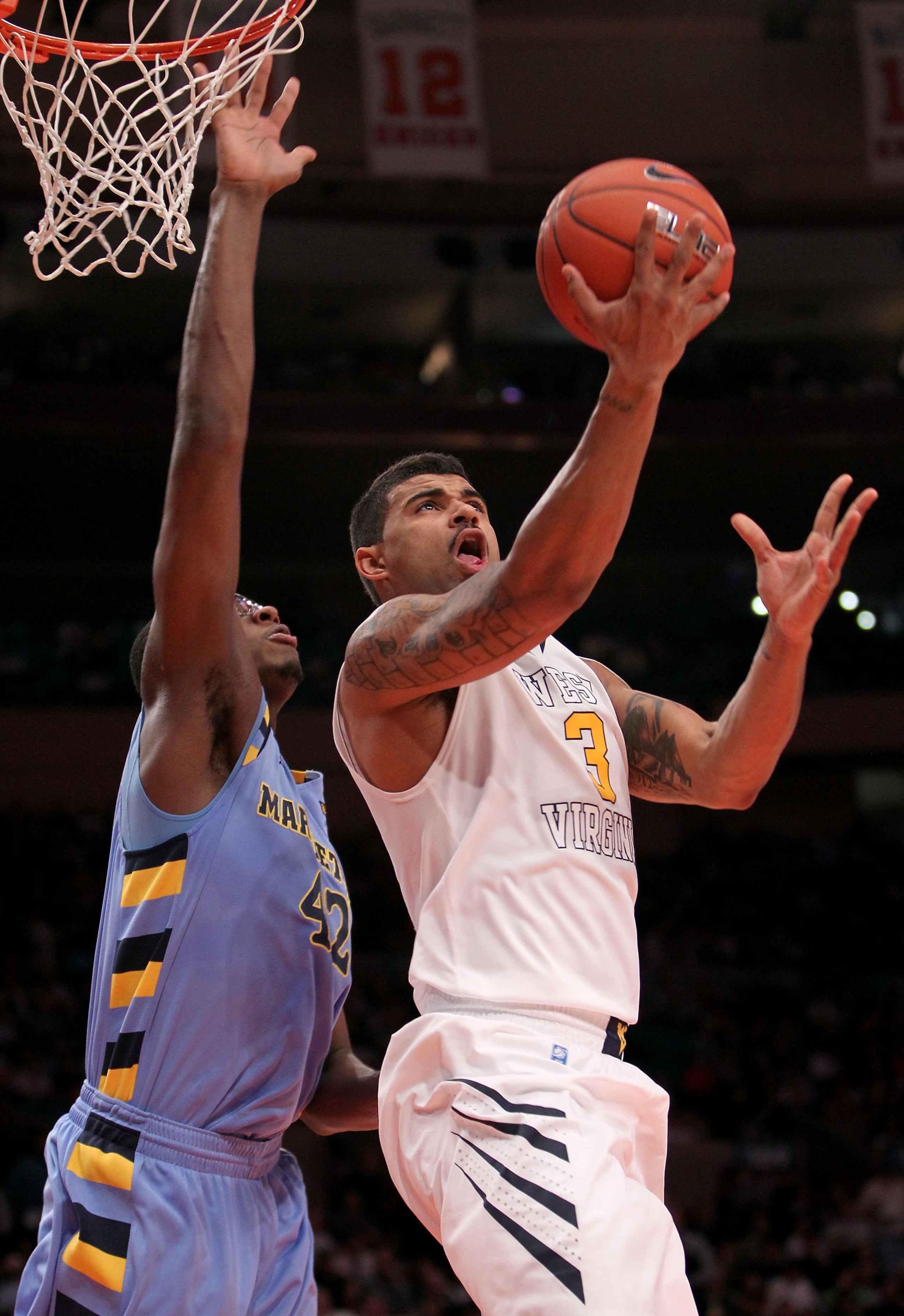NEW YORK, NY - MARCH 09: Casey Mitchell #3 of the West Virginia Mountaineers drives to the basket against Chris Otule #42 of the Marquette Golden Eagles during the second round of the 2011 Big East Men's Basketball Tournament presented by American Eagle O