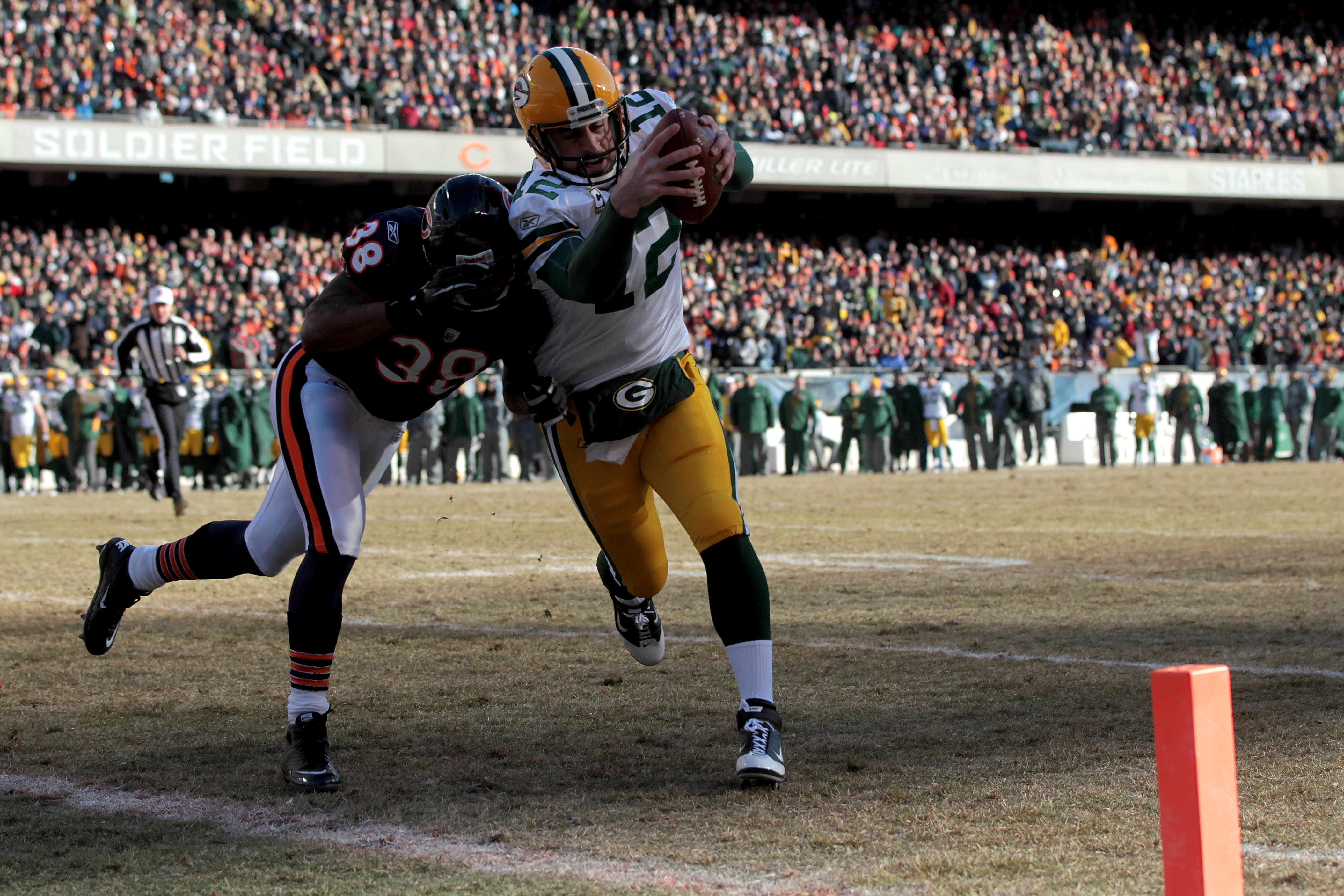 CHICAGO, IL - JANUARY 23:  Quarterback Aaron Rodgers #12 of the Green Bay Packers dives into the corner of the endzone for a one-yard touchdown run against Danieal Manning #38 of the Chicago Bears in the first quarter of the NFC Championship Game at Soldi