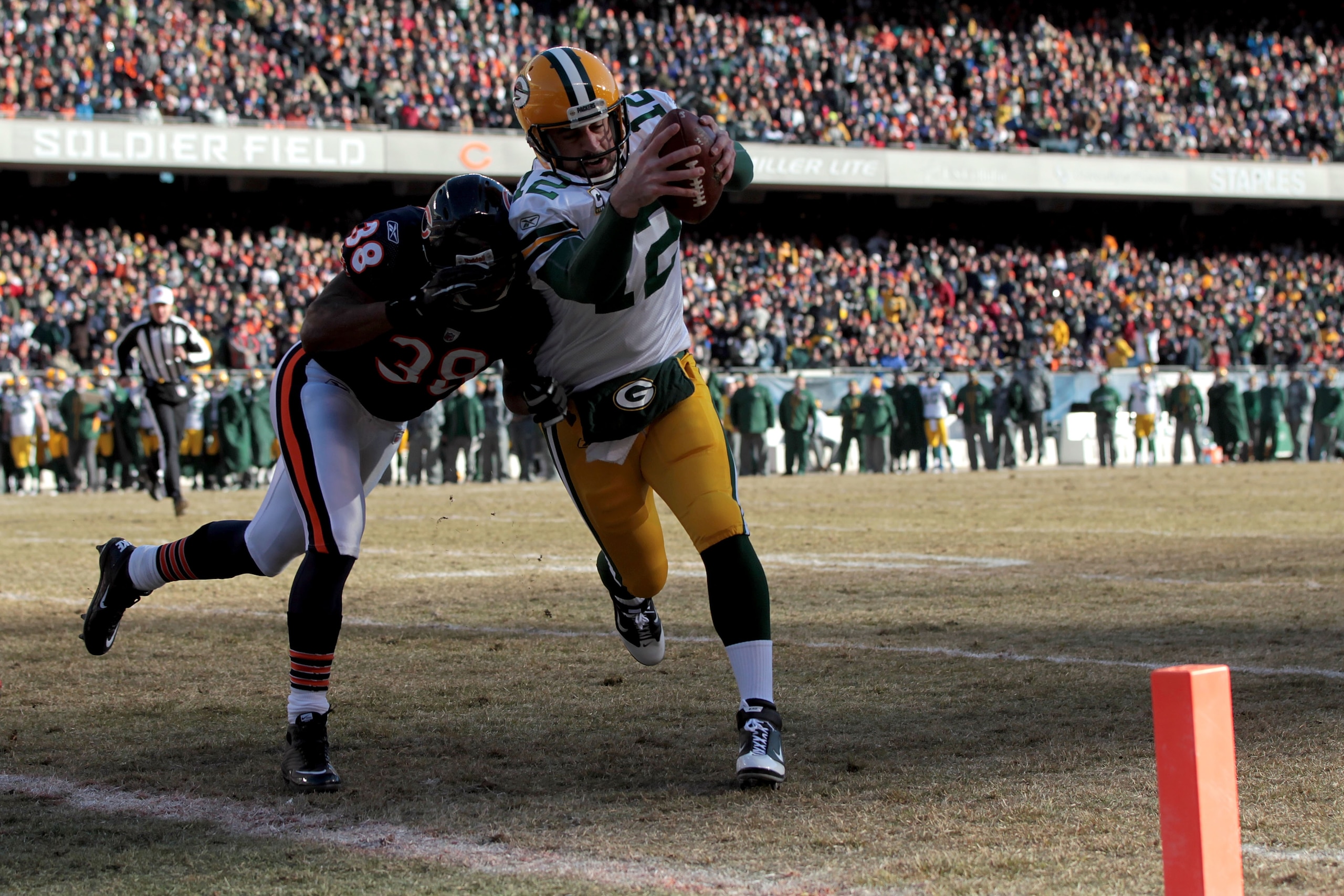 CHICAGO, IL - JANUARY 23:  Quarterback Aaron Rodgers #12 of the Green Bay Packers dives into the corner of the endzone for a one-yard touchdown run against Danieal Manning #38 of the Chicago Bears in the first quarter of the NFC Championship Game at Soldi